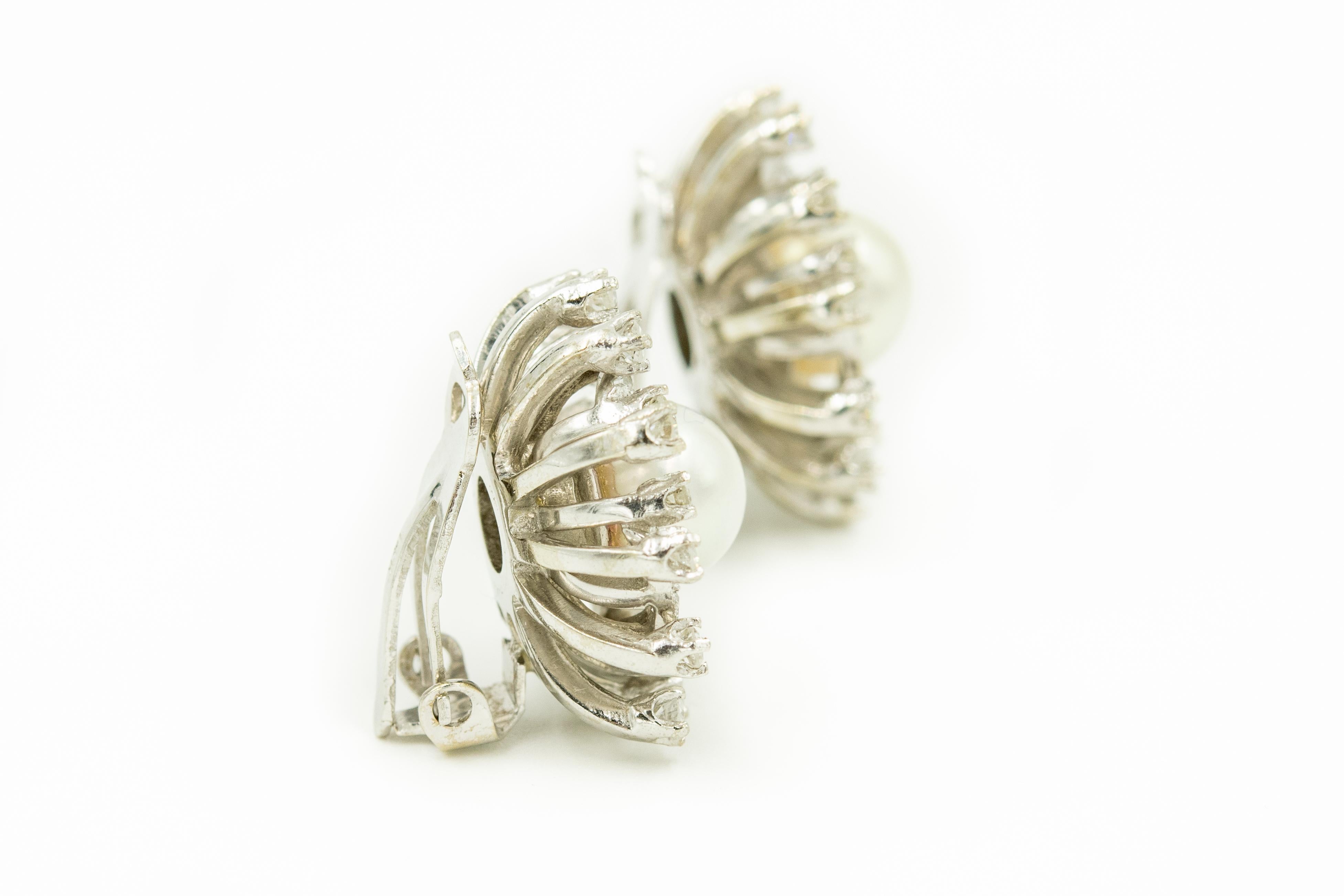 Finely made 14k white gold clip on earrings featuring a 7.55 mm cultured pearl in a diamond cluster round frame.  