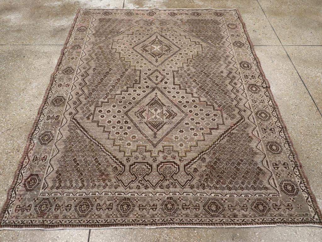 A vitnage Persia Afshar accent rug. A dense fill of row by row reversing tiny botehs fills the tan field corners and the sides of the subfield surrounding the wasp-waisted, rosette filled central motif with three lozenge points at each end. The