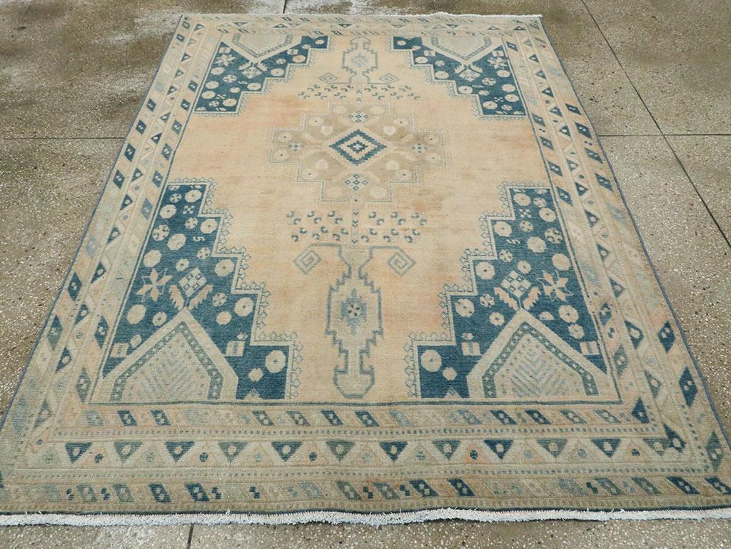 The deeply stepped straw field shows flowering vases at each end and a stepped salmon medallion with a nested diamond center. Dark blue corners with rosettes and nested, tall pentagons. Inner and outer minors with diagonal stripes and a central main