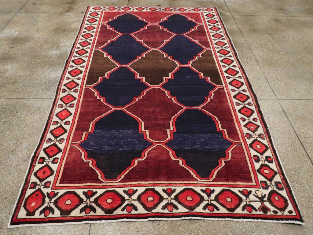 Alfombra de acento persa Bakhtiari vintage. Dos columnas de cartelas anchas lisas de color azul marino se alternan con paneles similares de color marrón rojizo, igualmente sin decorar y bien raspados, todo ello dentro de una celosía jaspeada de