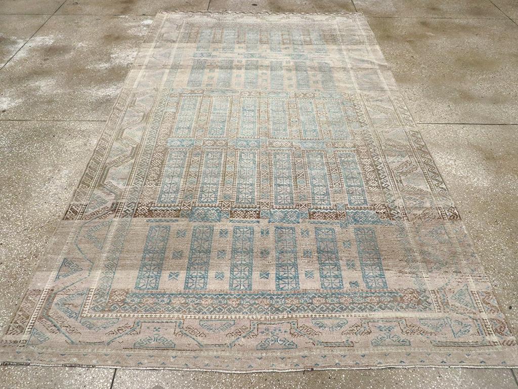 This large Baluchi tent carpet features a wool pile of asymmetric knots on a wool and cotton foundation. It displays a geometric pattern of five echelons, each consisting of six tall rectangles rendered in light slate, with mostly dark brown