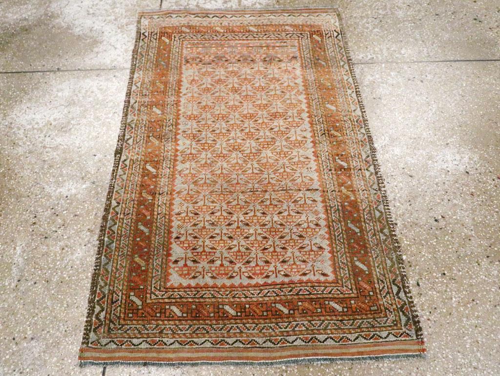 Un tappeto persiano Baluch vintage. Questo piccolo formato di spargimento è popolare tra i tessitori Baluch rustici e lo sono anche i terreni di cammello, come in questo caso con file a mezza goccia di fiori stilizzati, inseriti in un ampio sistema