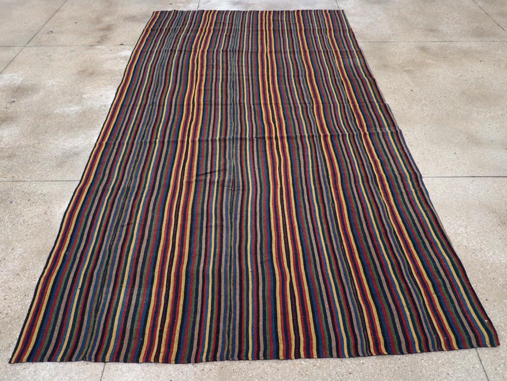This Mid-20th century Persian Flatweave Kilim rug, measuring 6' 4
