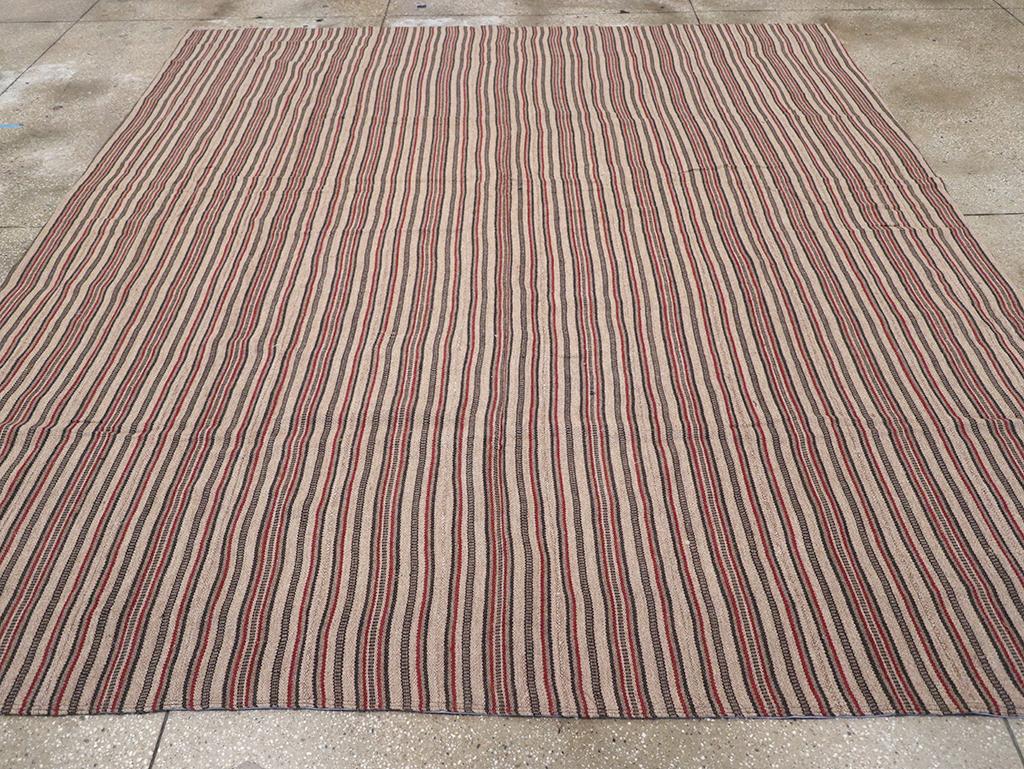 Ce tapis persan Kilim à tissage plat du milieu du 20e siècle, mesurant 9' 5