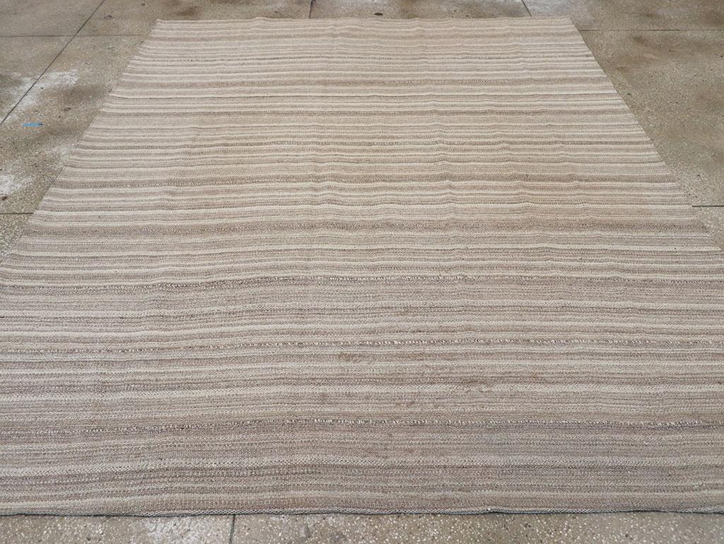 Esta alfombra Kilim persa de tejido plano de mediados del siglo XX, que mide 2,8 m x 3,8 m, presenta un sereno diseño de rayas horizontales en una paleta suave y neutra. Sutiles bandas de beige, topo y marfil fluyen por la superficie, creando una