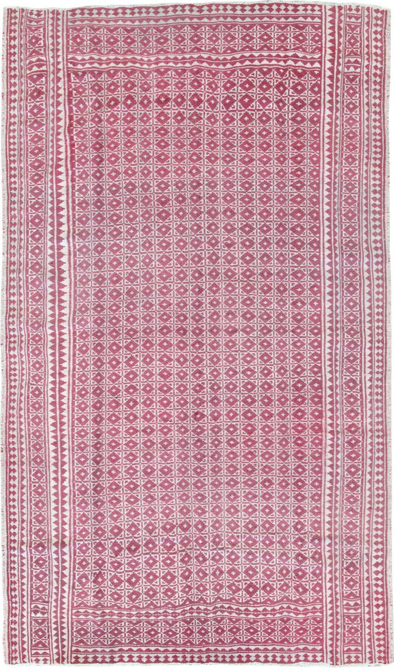 Un tappeto persiano vintage a trama piatta reversibile Rug & Kilim. Fondamentalmente bitonale, il campo e il bordo principale sono costituiti da quadrati rosa e avorio che racchiudono diamanti, mentre i bordi secondari mostrano piccoli motivi a