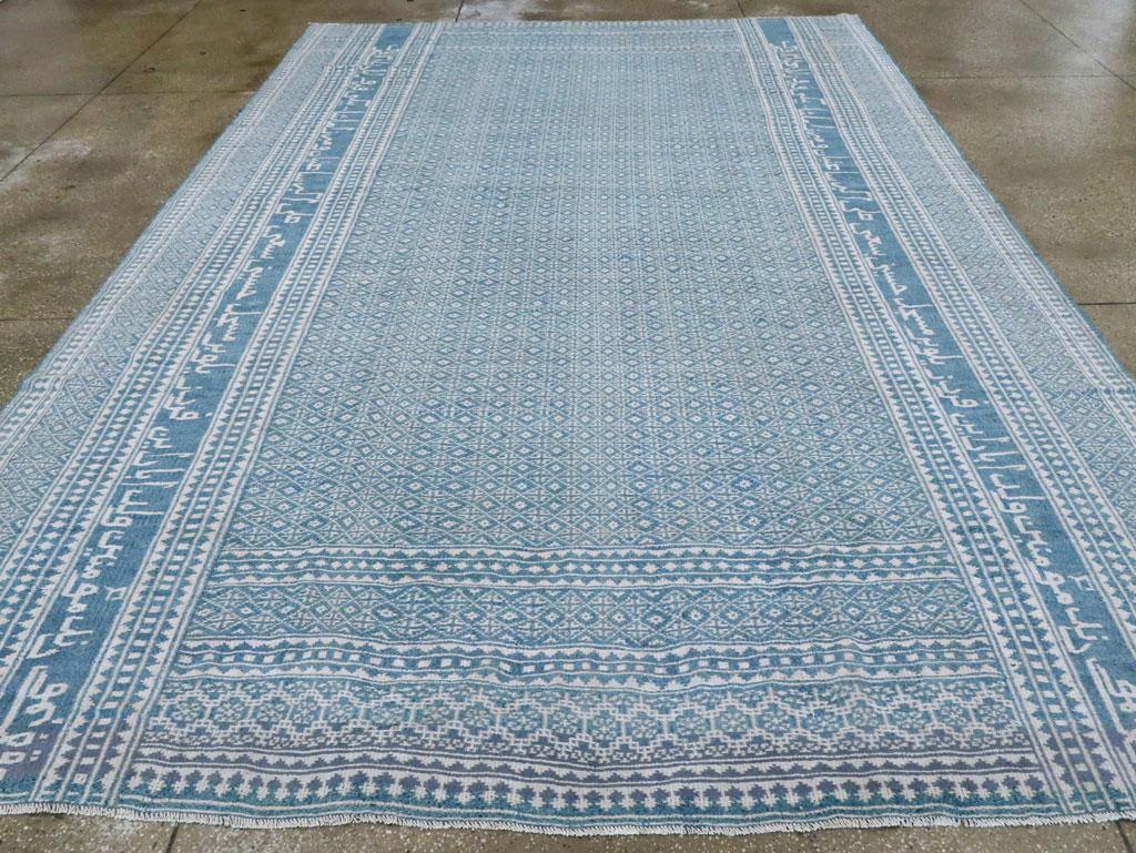 Blaue Seitenränder mit einer Mischung aus fünf signifikanten Streifenmustern rahmen ein blaues Feld ein, in dem Zeile für Zeile und Spalte für Spalte eine präzise Anordnung von kleinen Quadraten mit Rauten zu sehen ist. Die Enden sind sauber