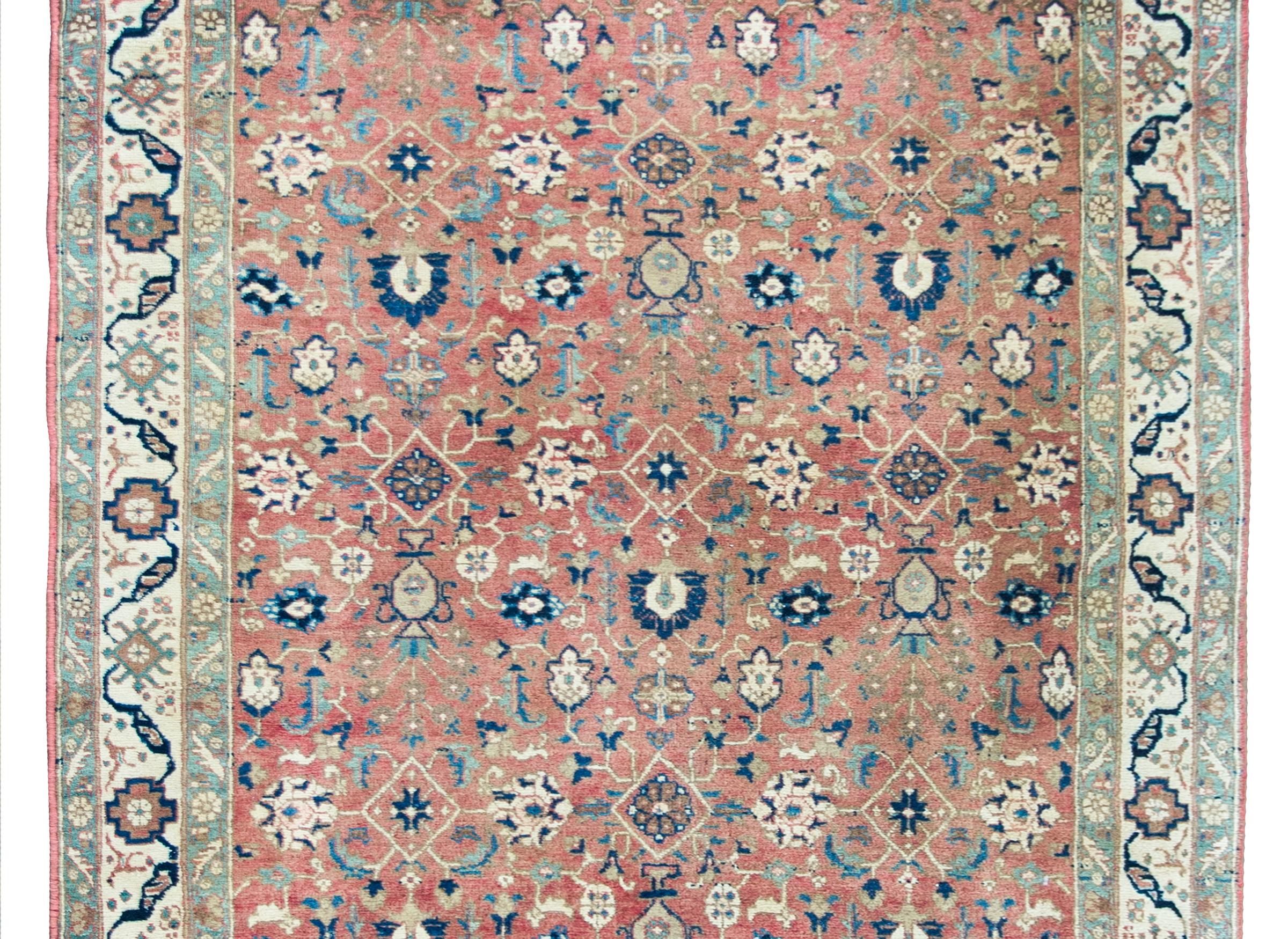 A beautiful mid-20th century Persian Khoy rug with an all-over floral trellis pattern woven in repeated large-scale flowers and vases potted with trees-of-life, set against an orange background, and surrounded by a simple border with more stylized
