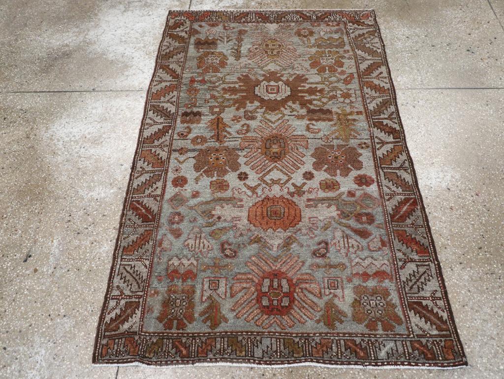 Un tapis persan kurde vintage. Le champ gris perle s'abrase en ardoise vers une extrémité et présente un motif de palmettes symétriques et dentelées et de rosettes rayonnées communes à plusieurs types de tapis ouest-persans.  La bordure de feuilles