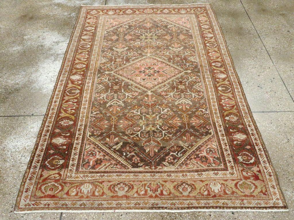 Un tapis d'appoint persan Malayer vintage. Un médaillon en losange à franges serrées avec des coins en suite est placé sur un champ brun avec un léger motif de treillis entourant des fleurs et des tiges stylisées. La bordure principale abrasée