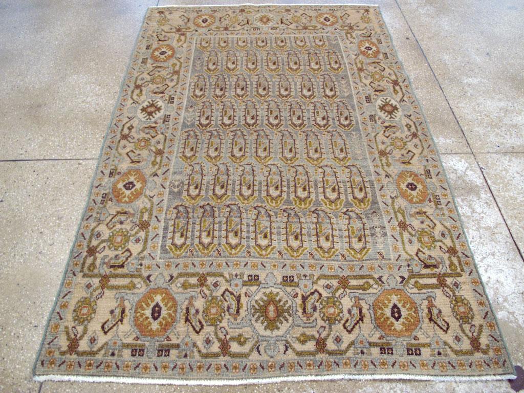Un tappeto d'accento persiano vintage Malayer. Sei file e mezzo sfalsate di boteh color mattone e ruggine sono tutte rivolte verso sinistra sul fondo grafite chiaro di questo spargimento di villaggio persiano occidentale a motivi tessili, mentre