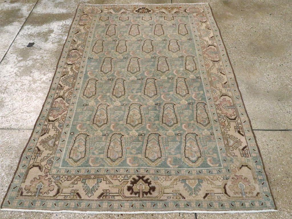 Ein alter persischer Malayer-Teppich. Zwei dunkelbraune, gezackte Palmetten akzentuieren die Strohbordüre, die wiederum über dem blassblau-grauen Feld mit einem Textilmuster aus sechseinhalb Reihen nach rechts gerichteter Botehs mit schmalen