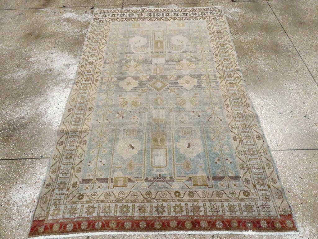 Ein alter persischer Malayer Akzentteppich. Der Grund ist von einem mittleren Graublau zu einem hellen Blaugrau abradiert und trägt ein flächendeckendes, halbgeometrisches Muster aus langen, geraden Arabesken, feldhohen Blütenstäben auf jeder Seite