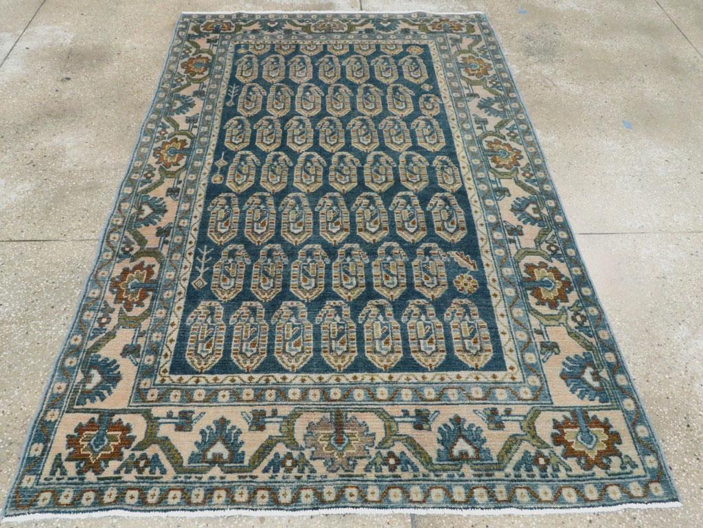 The dark slate blue field shows seven reversing, offset rows of complete semi-geometric upright botehs, within a straw main border with finger fringed reversing ragged pyramidal palmettes. Rust touches throughout. Rustic, medium weave scatter from