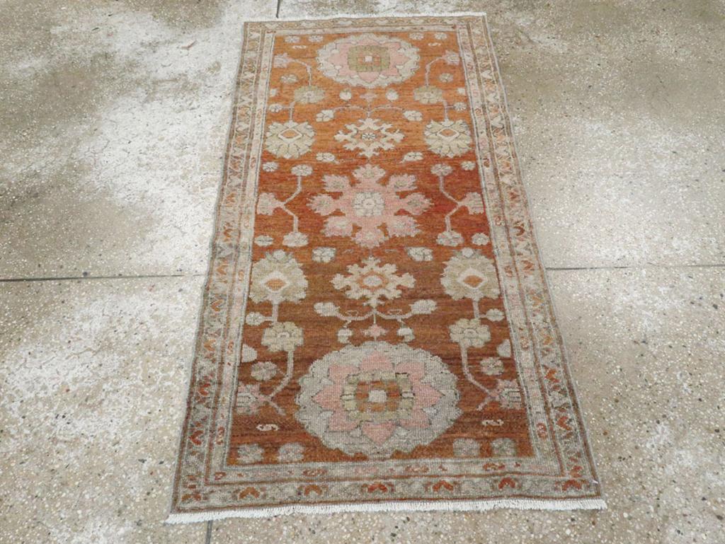 Ein alter persischer Malayer-Teppich. Dieses kleine, rustikale westpersische Streumuster zeigt ein sattes rostbraunes Feld, in dessen Mitte ein Medaillon mit einer oktoförmigen Palmette steht. Darüber und darunter befinden sich grobe Ellipsen, die