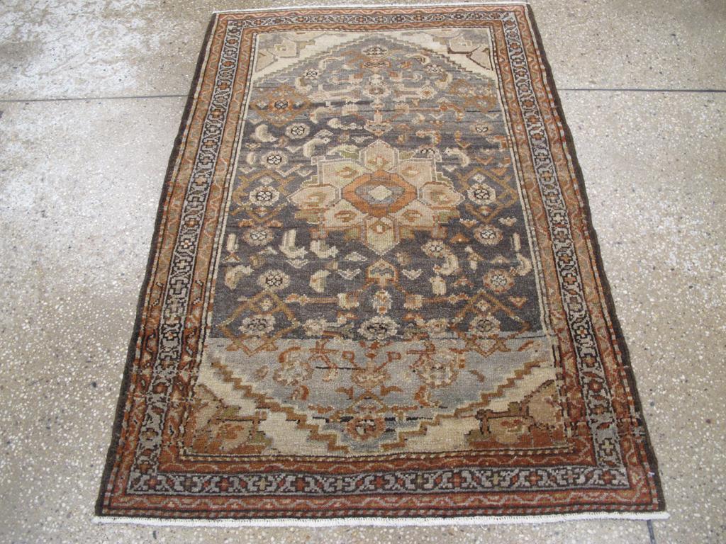 Un tappeto persiano vintage Malayer. Un medaglione a forma di ottavo di cammello è incastonato sul campo di ardesia abrasa con un disegno Herati frammentato. I medaglioni dei quarti riempiono gli angoli del campo. Un bordo grigio-azzurro di barre e