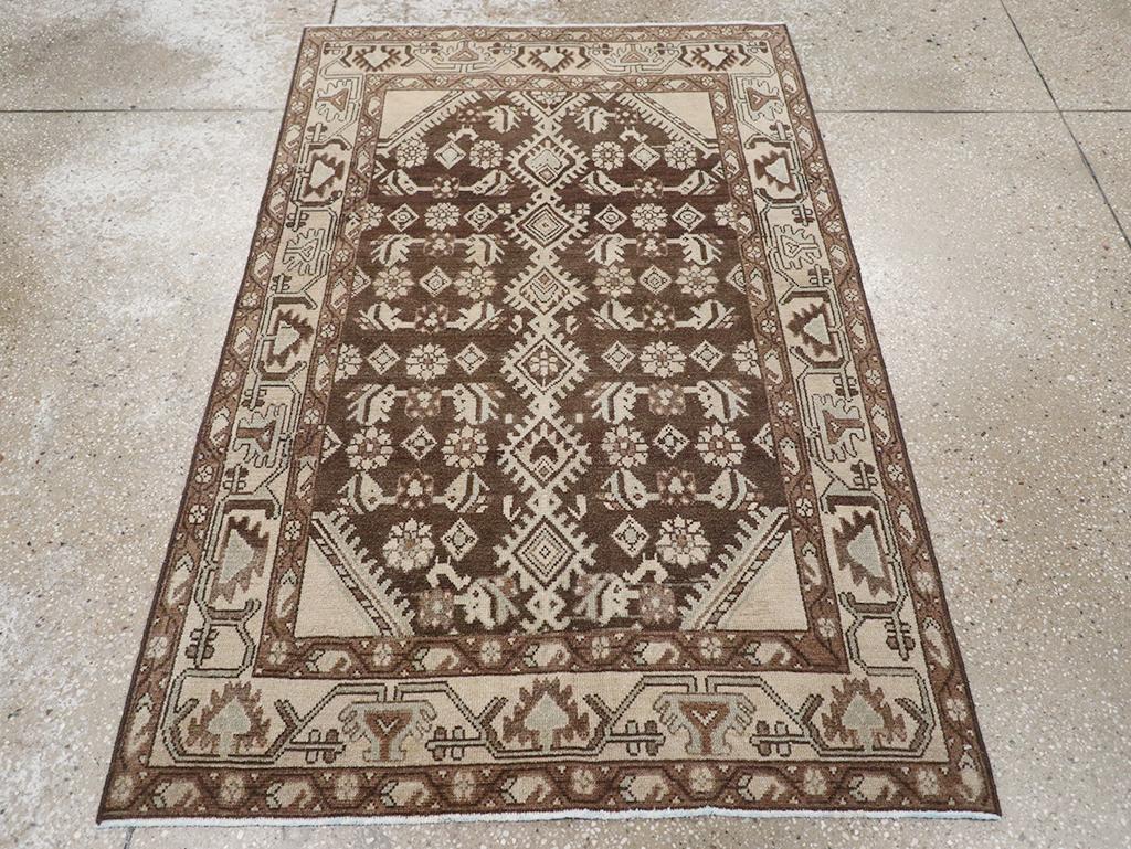 Ein Wollflor mit symmetrischen Knoten auf einer Baumwollunterlage. Das fast schwarze Feld zeigt eine zentrale Säule aus sieben kleinen, gefransten Diamanten, flankiert von locker angeordneten gebogenen Blättern, kleinen Diamanten und Rosetten in