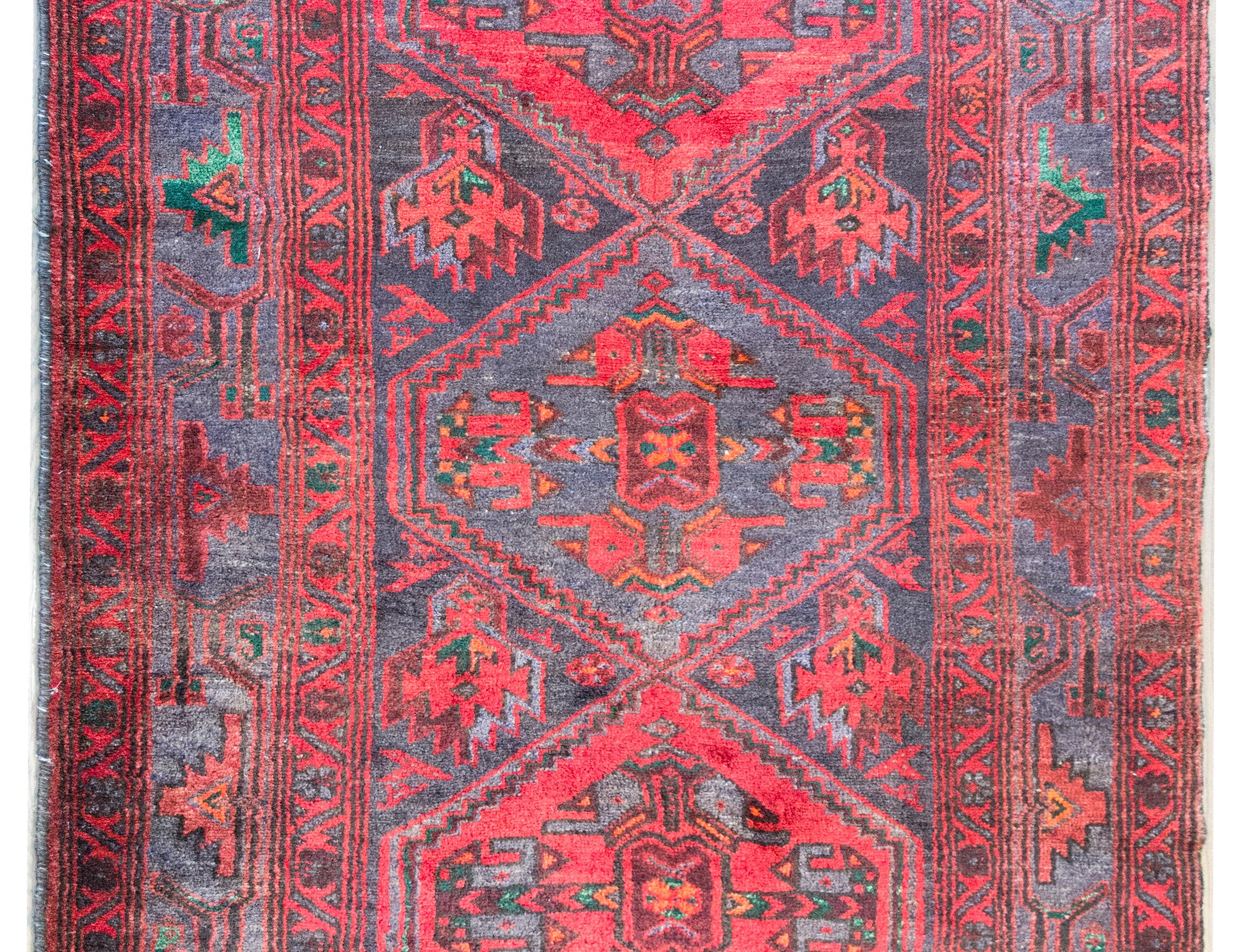 Questo tappeto persiano Mazlaghan della metà del XX secolo è un vivace esempio di artigianato tradizionale proveniente dalla regione di Mazlaghan, nell'Iran occidentale. Rinomati per i loro audaci motivi geometrici e le ricche palette di colori, i