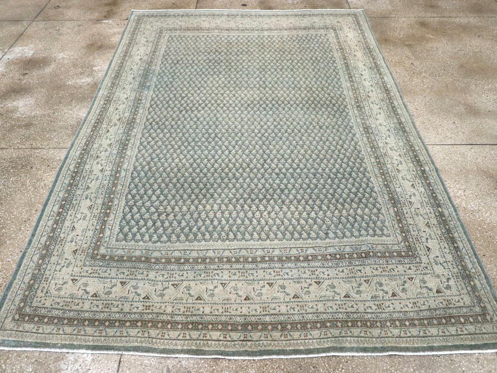 A wool pile of symmetric knots on a cotton foundation. This Persian-format city carpet closely follows an urban Sarabend archetype with rows and offset rows of tiny uniform reversing botehs on a slate/charcoal field. The ecru main border shows a