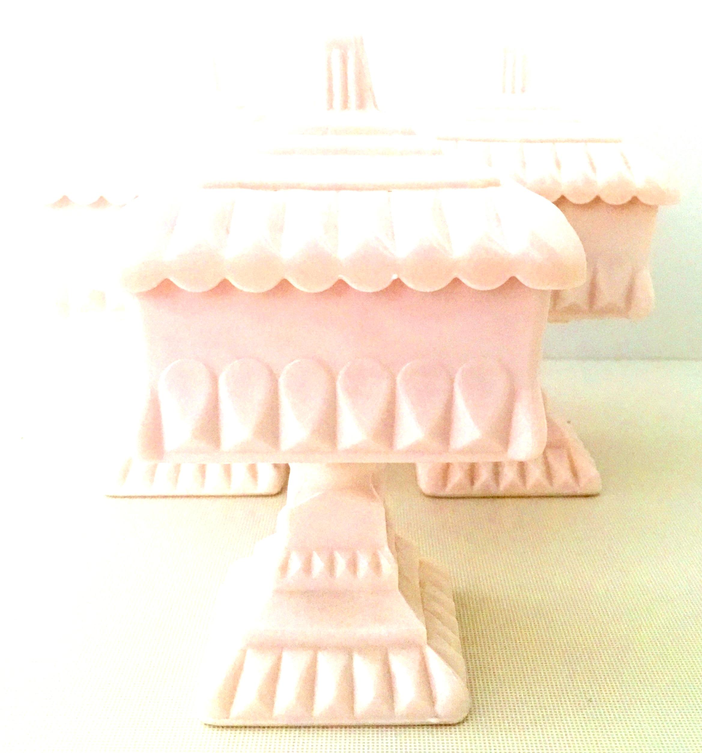 Mid-20th century pink milk glass footed bowls, set of three pieces. Set includes three pink milk glass footed and lidded square bowls.