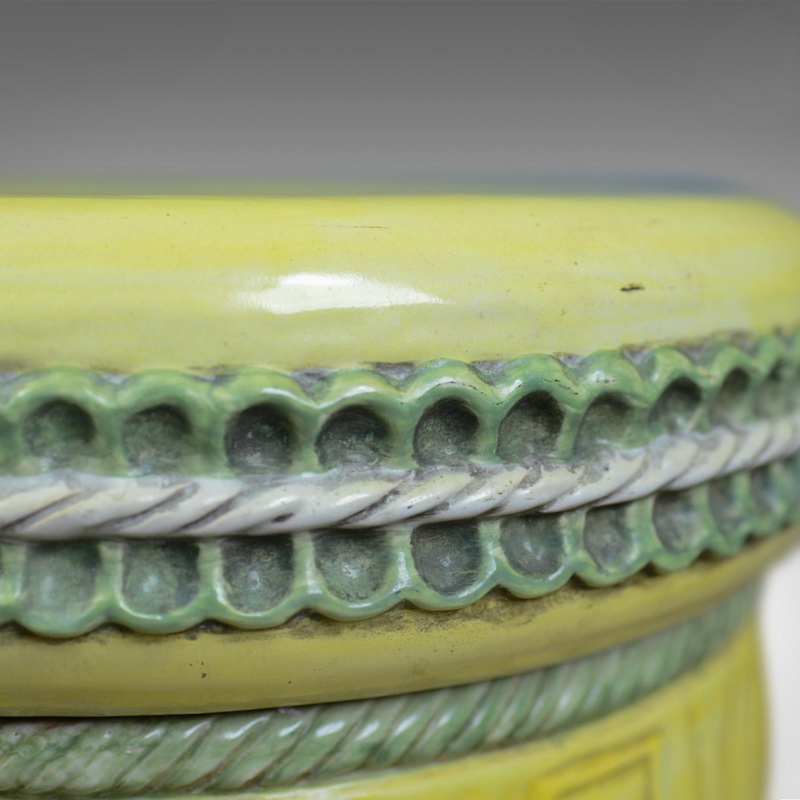 This is a mid-20th century glazed terracotta plant stand, an Italian jardiniere or garden stool.

Attractive lemon and green hues
Desirable aged patina
Shallow dished top with rope and pleat edge
Swagged and tassled base over flared