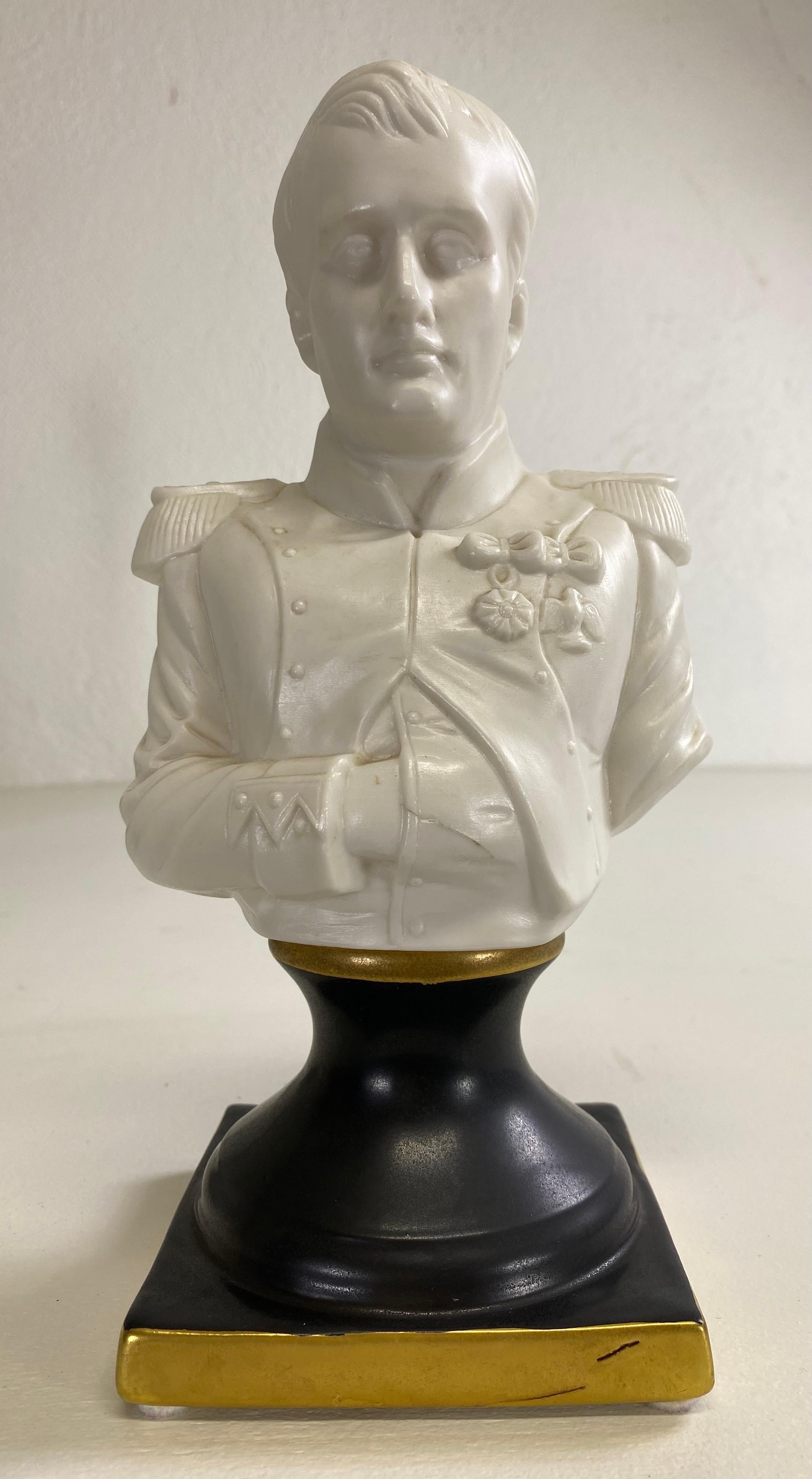 This is an early 20th century porcelain bust of the French emperor Napoleon Bonaparte. This classical bust is in a bisque white porcelain at the top with a black porcelain base trimming gold. This bust is artist signed on the reverse.