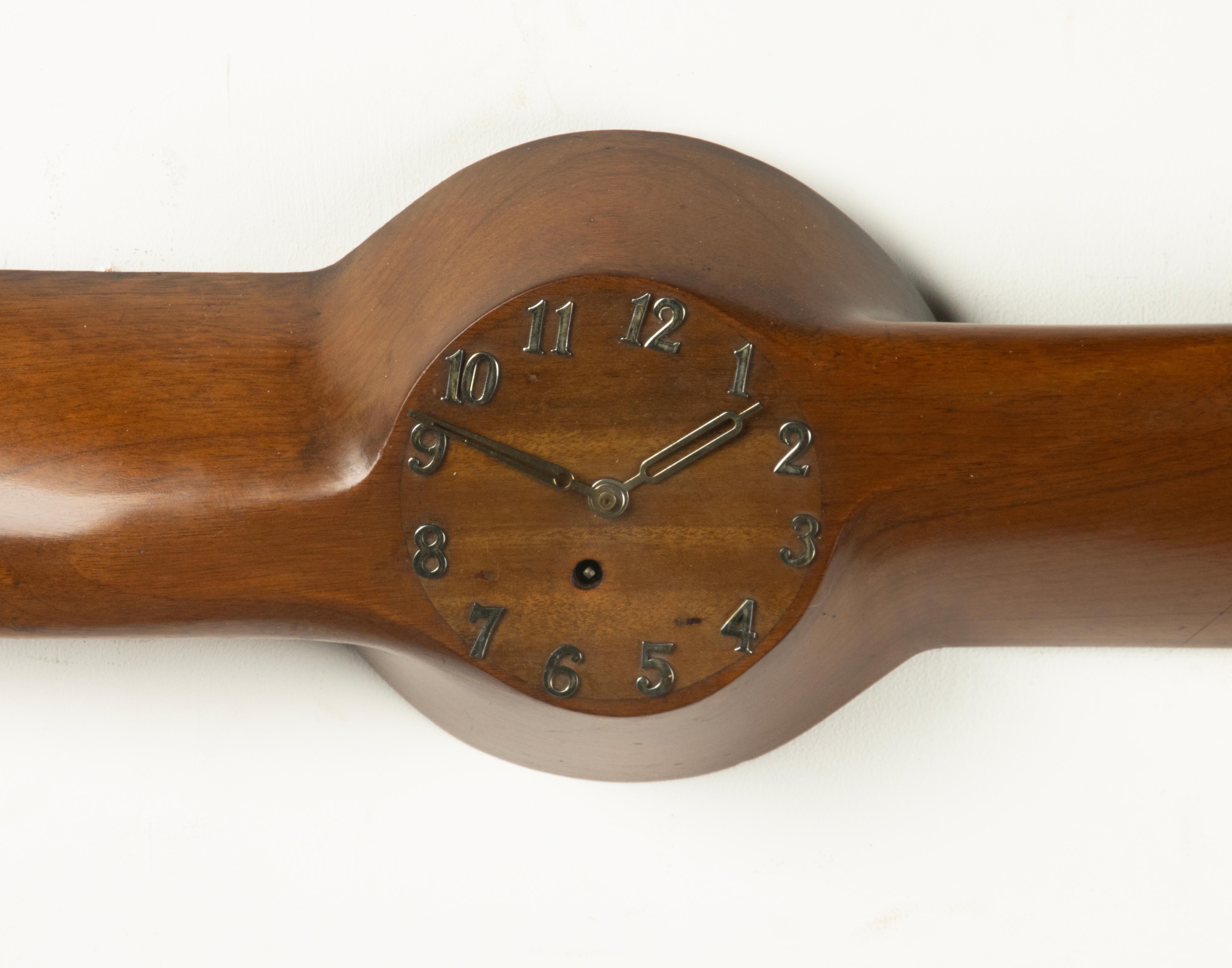 Striking mid-20th century wall clock designed in the form of an airplane propeller. Crafted in richly toned wood with a beautiful warm patina, the piece combines functional design with aviation-inspired style. The clock is integrated in the