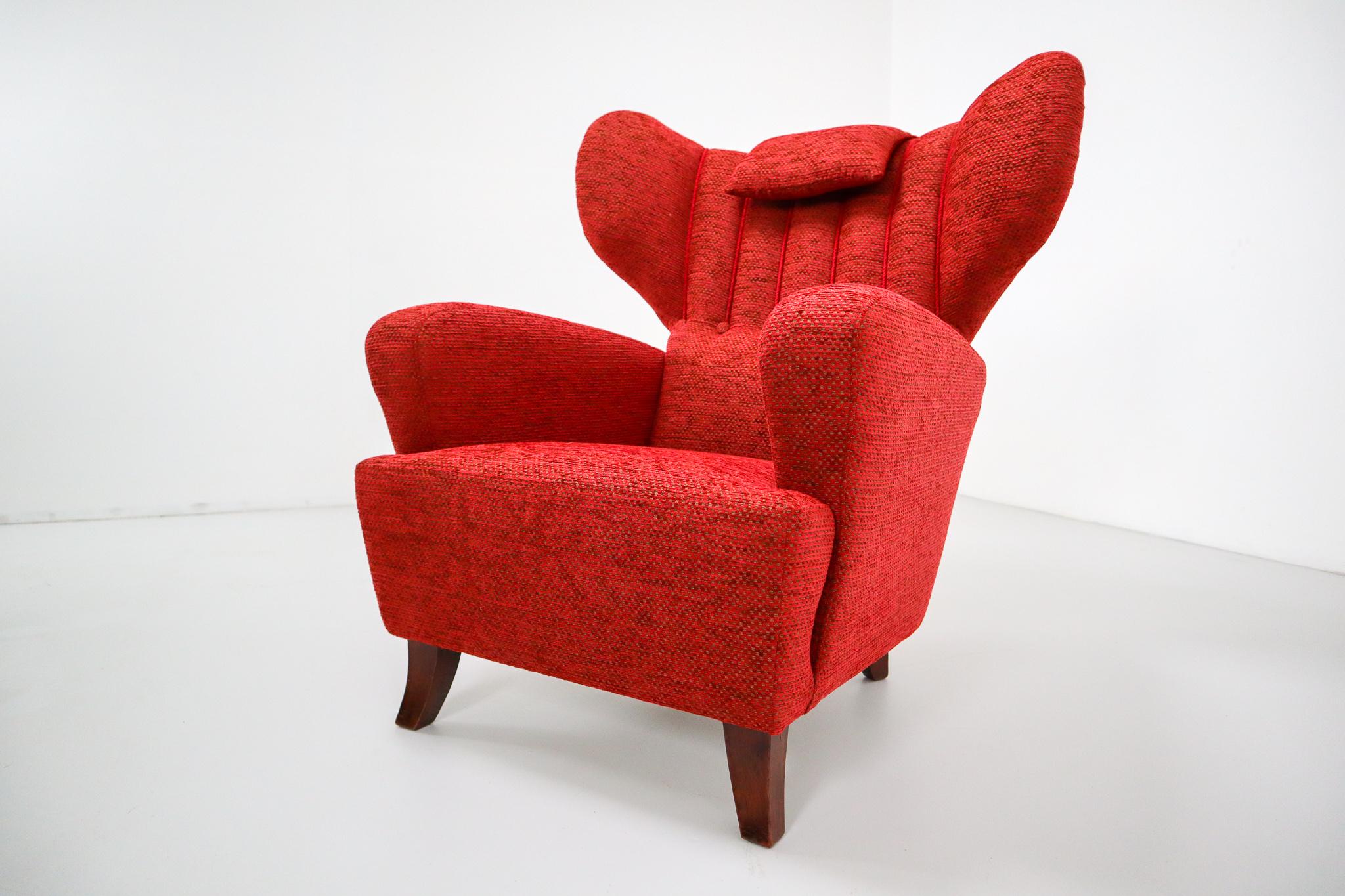 Mid-20th century red reupholstered wingback chair, Austria, 1930s .This chair is newly upholstered with a beautiful red new fabric. The wingback shows beautiful curves and organic lines. Due the high back and 'wings' or 'ears' this chair give a warm