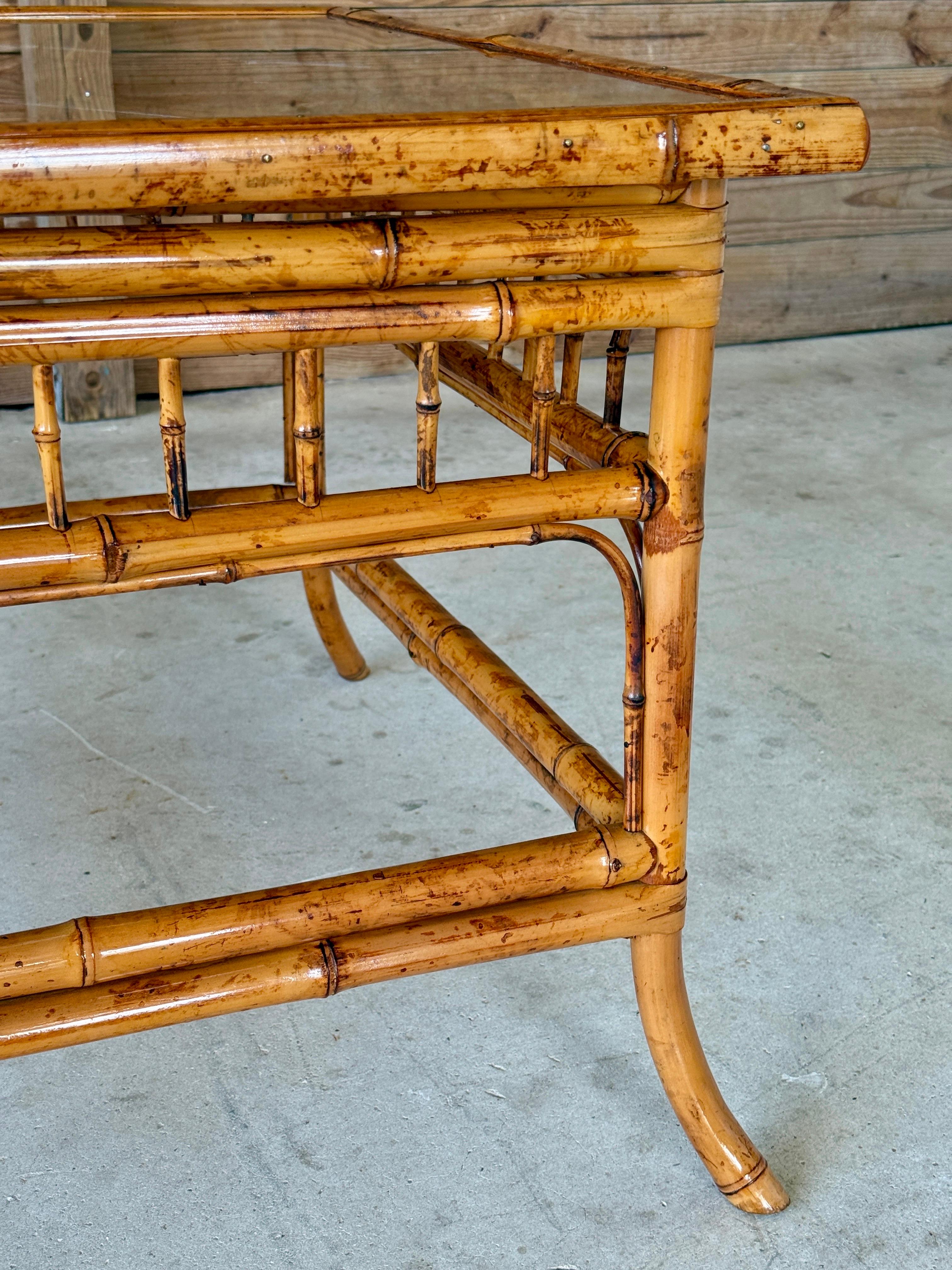 A stunning Mid-20th Century bamboo table in the Brighton Pavilion style, fully refinished and ready to anchor your space with tropical elegance.
Featuring a square silhouette, slightly flared legs, and a decorative geometric bamboo fretwork beneath