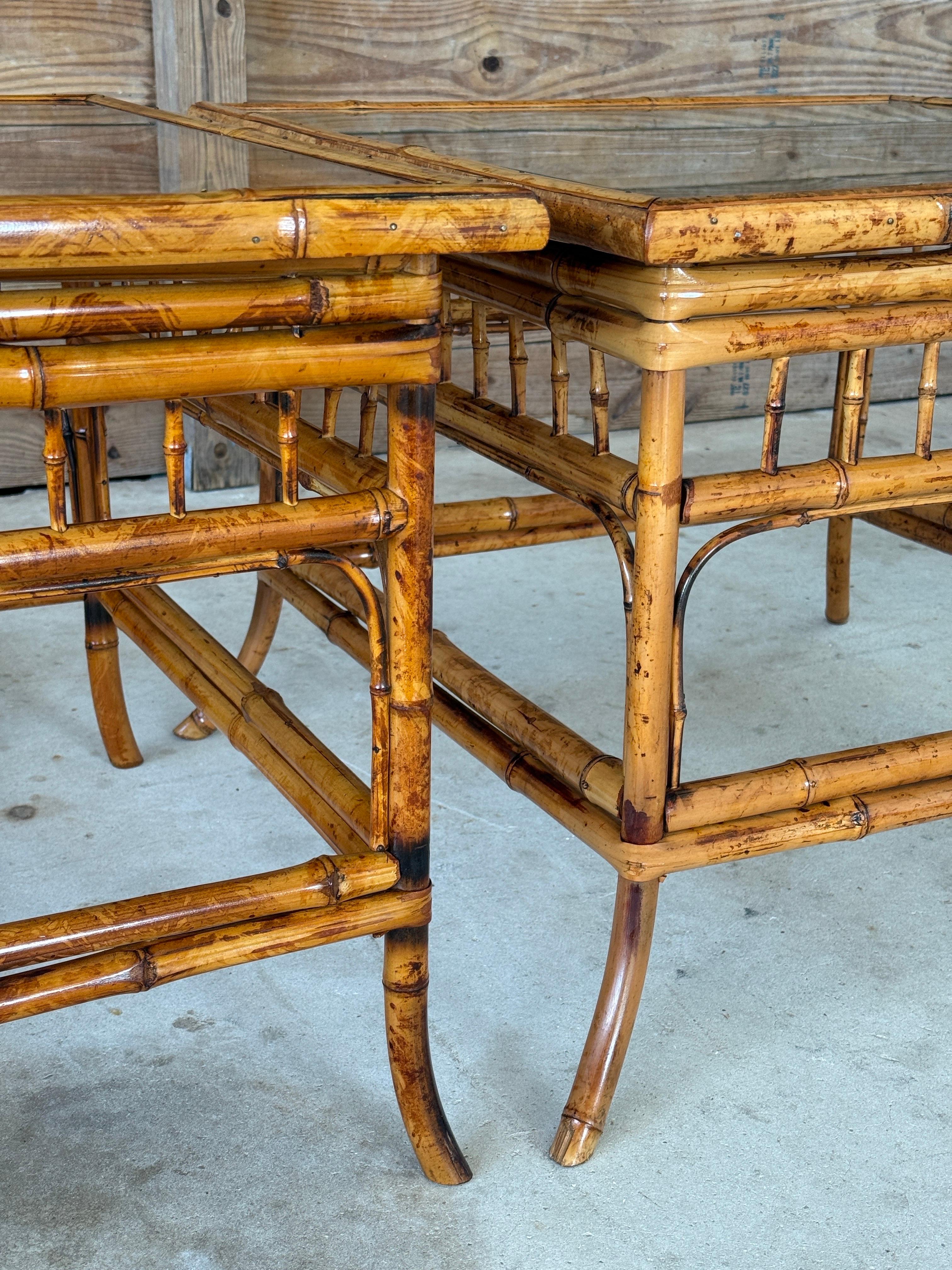 A pair of Mid-20th Century bamboo side tables in the sought-after Brighton Pavilion Chippendale style. Each table showcases a beautifully detailed bamboo frame with latticework stretchers and spindled aprons, topped with new inset glass for a clean