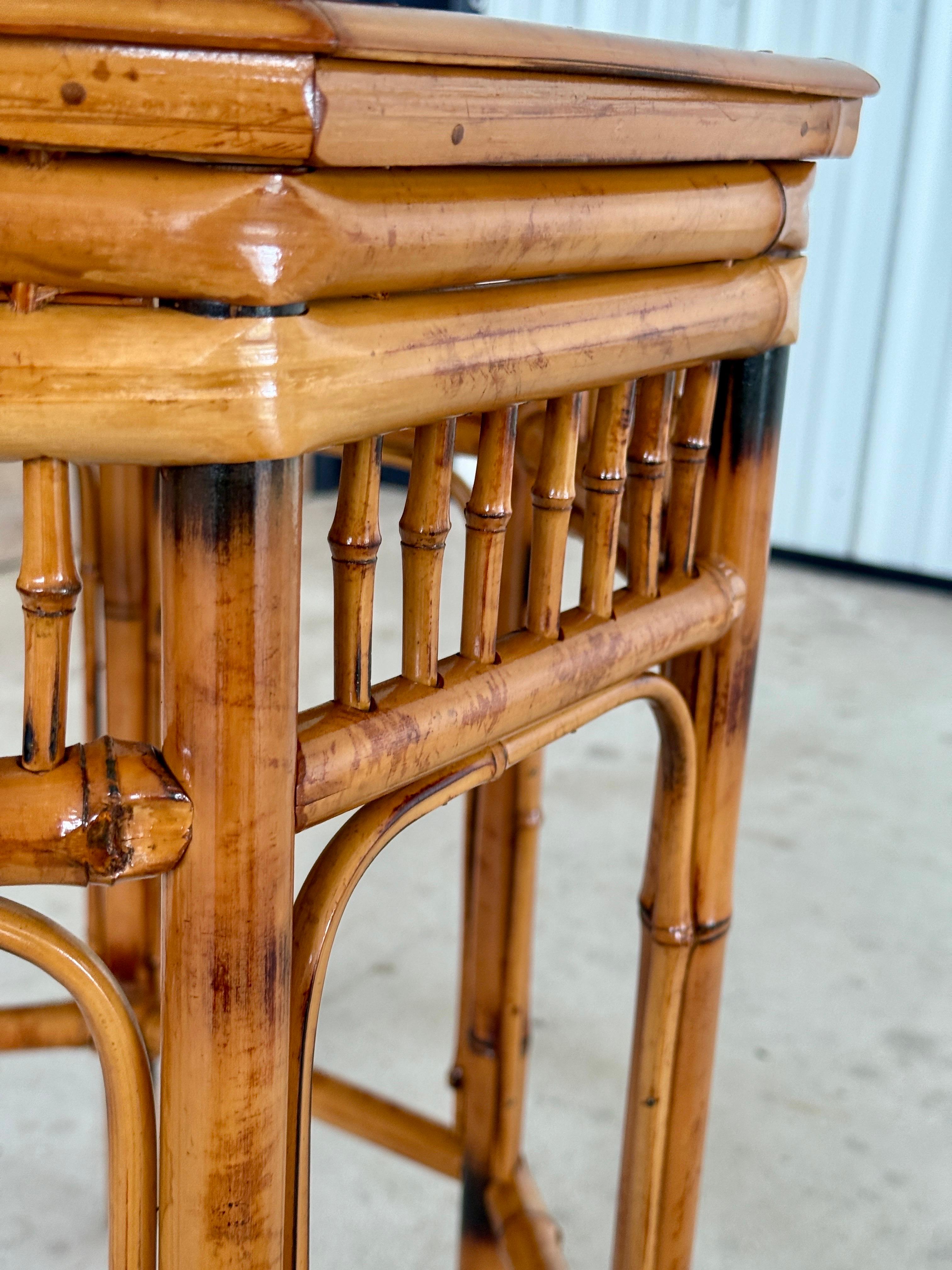 Refinished and restored with care, this mid-20th century burnt bamboo side table embodies the charm of the Brighton Pavilion style. The octagonal frame features spindled accents and a warm, hand-torched bamboo finish topped with its original inset