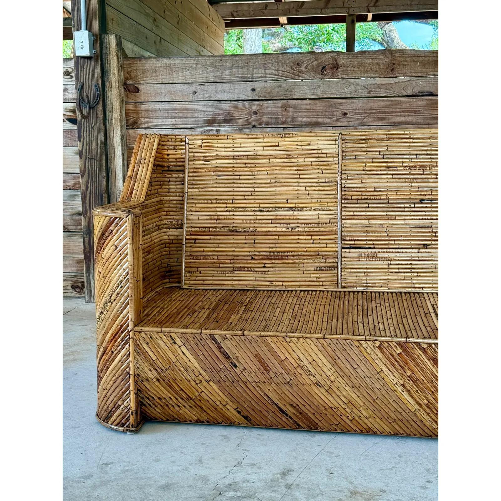 A bold and sculptural Mid-20th Century split rattan sofa, fully restored and showcasing exceptional craftsmanship. The geometric frame is wrapped in diagonally patterned rattan, highlighting warm natural tones and a dynamic chevron design along the