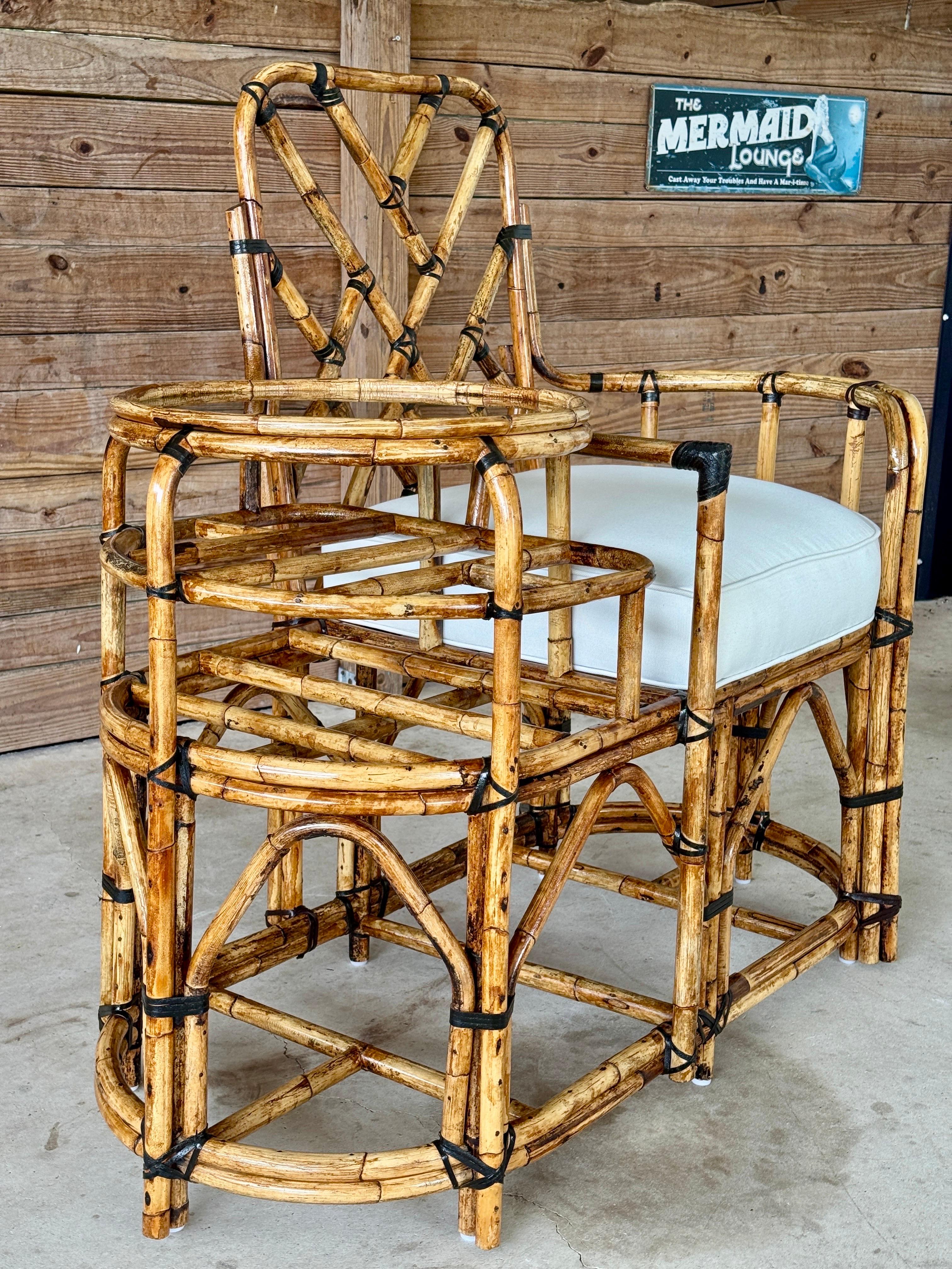 A rare and sculptural Mid-20th Century rattan settee featuring a Chippendale back design, gracefully arched supports, and integrated side table with original smoked glass top. The frame has been fully restored, showcasing the natural beauty of the