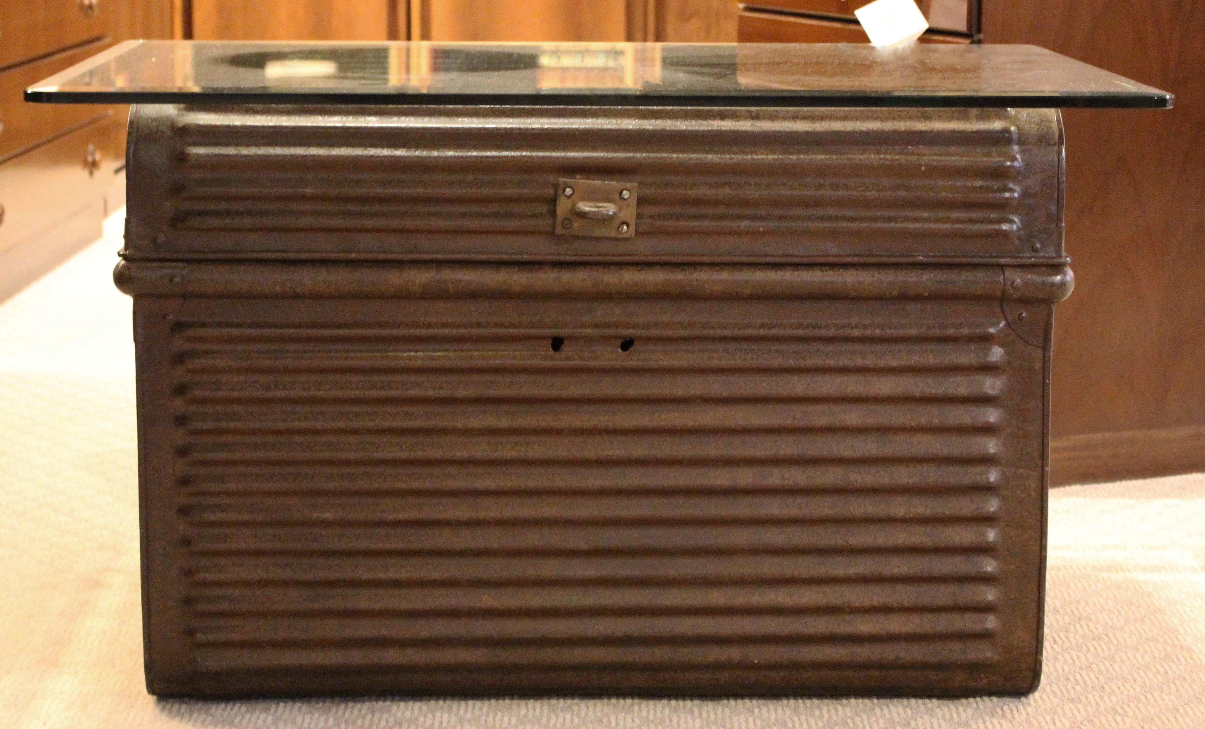 Ribbed metal trunk with handles - wonderful old original finish. Red painted interior with remnants of paper labels. English, mid-20th century. Now with glass top for a coffee table. Trunk: 30 1/2
