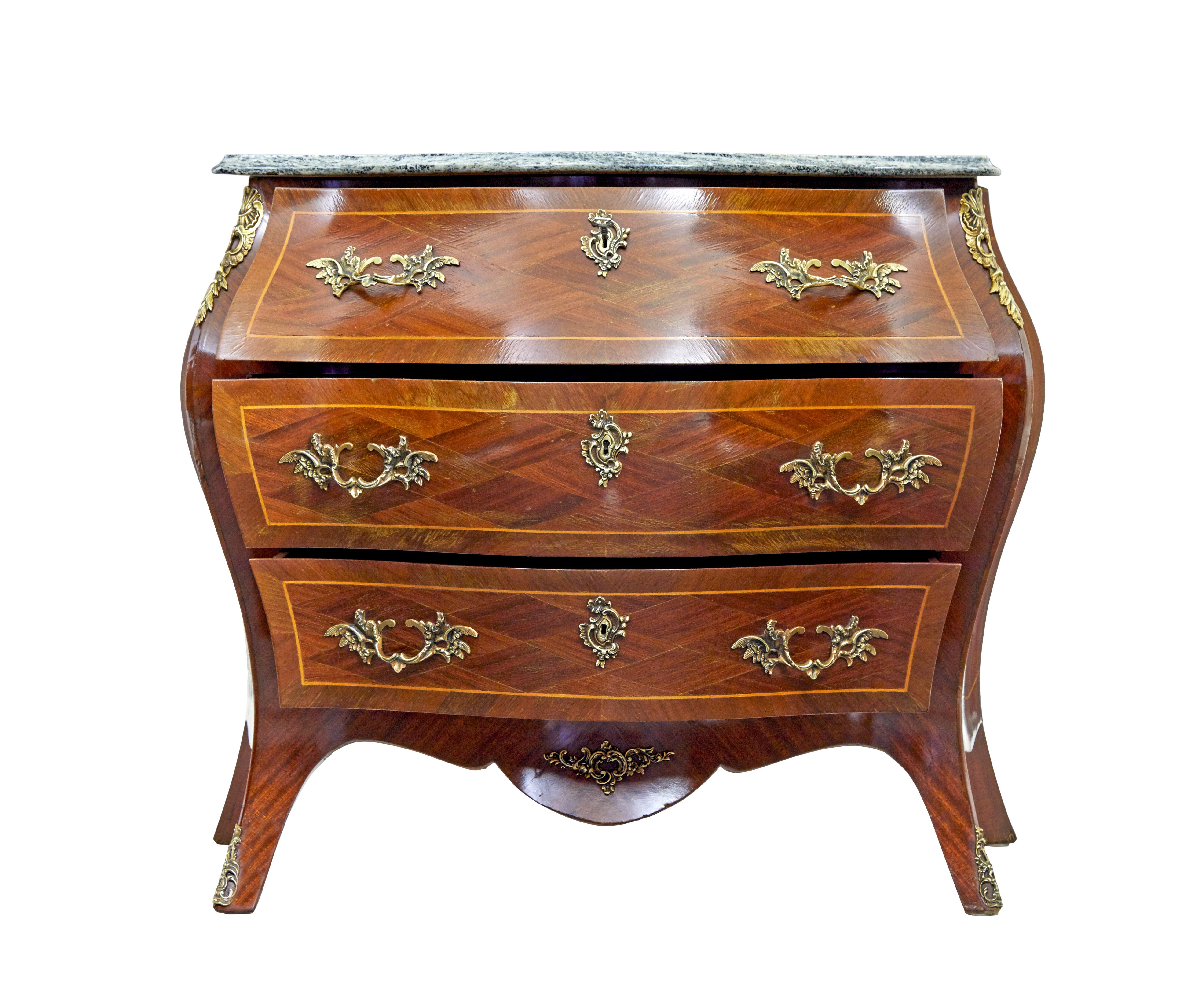 Mid 20th century rococo revival commode circa 1950.

Bombe shaped 3 drawer commode made in mahogany and kingwood, with shaped marble top. Green and grey marble is loose fitting for easier movement and shipping.

Arranged mahogany veneers with