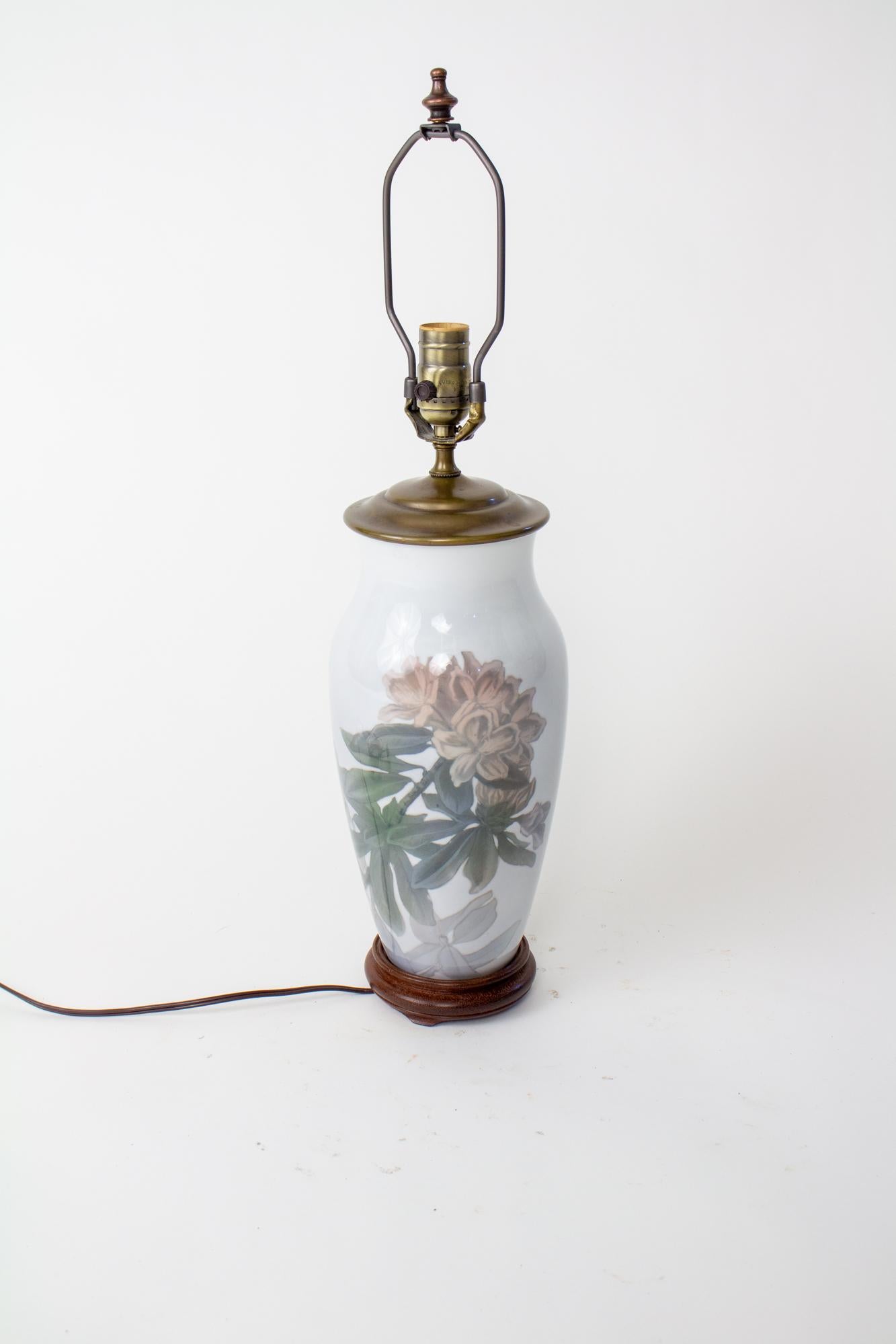 Lampe de table en rhododendron du milieu du 20e siècle de Royal Copenhagen. Vase du milieu du 20e siècle transformé en lampe de table. Motif de rhododendrons roses poussiéreux sur fond gris clair. Base en bois sculpté, bouchon de vase en laiton.