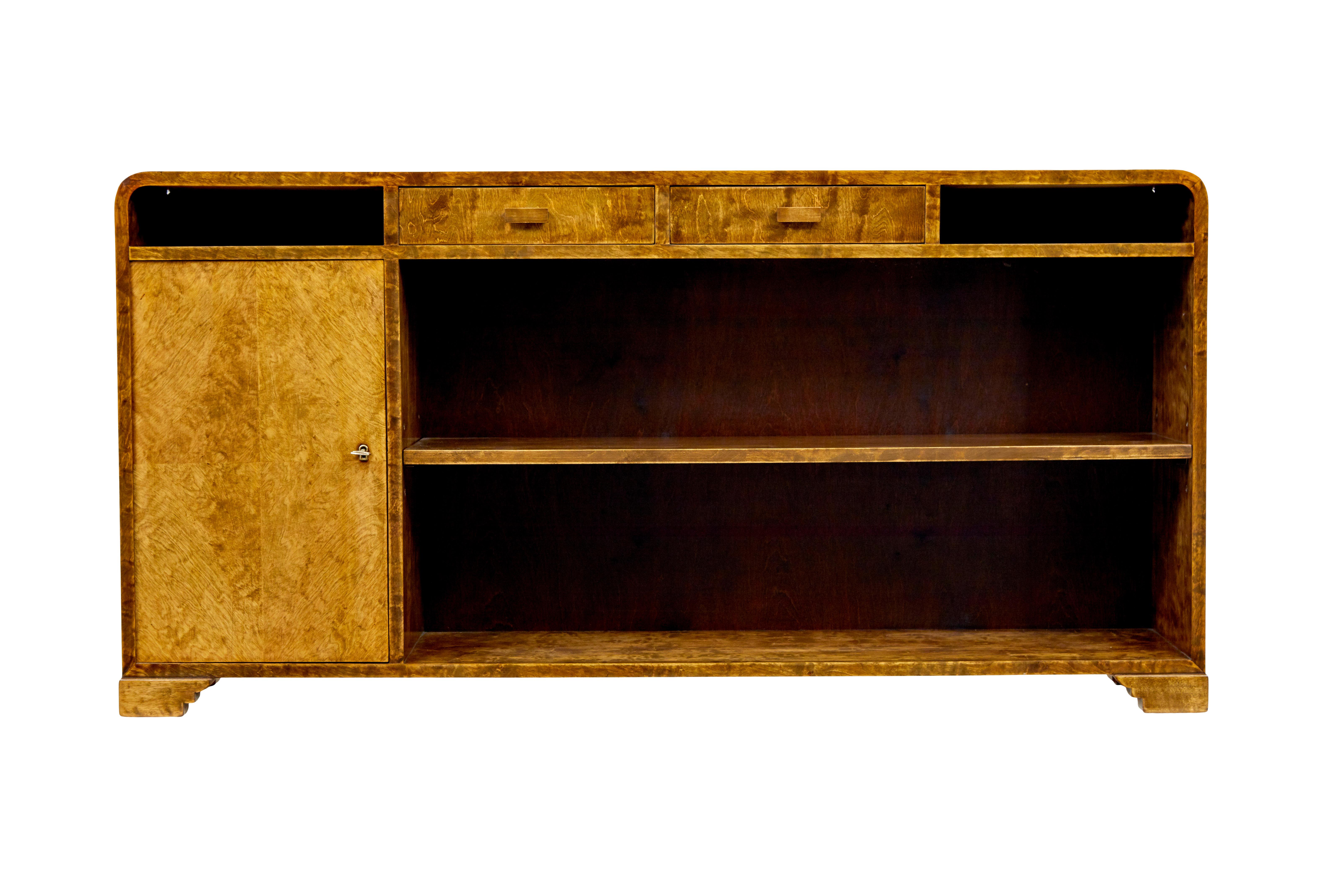 Mid 20th century Scandinavian birch bookcase by SMF Bodafors circa 1950.

Stunning burr birch low bookcase with rich golden colour.  Shaped top with 2 drawers below the top surface and 2 open apertures for storage.

Single door cupboard to the left