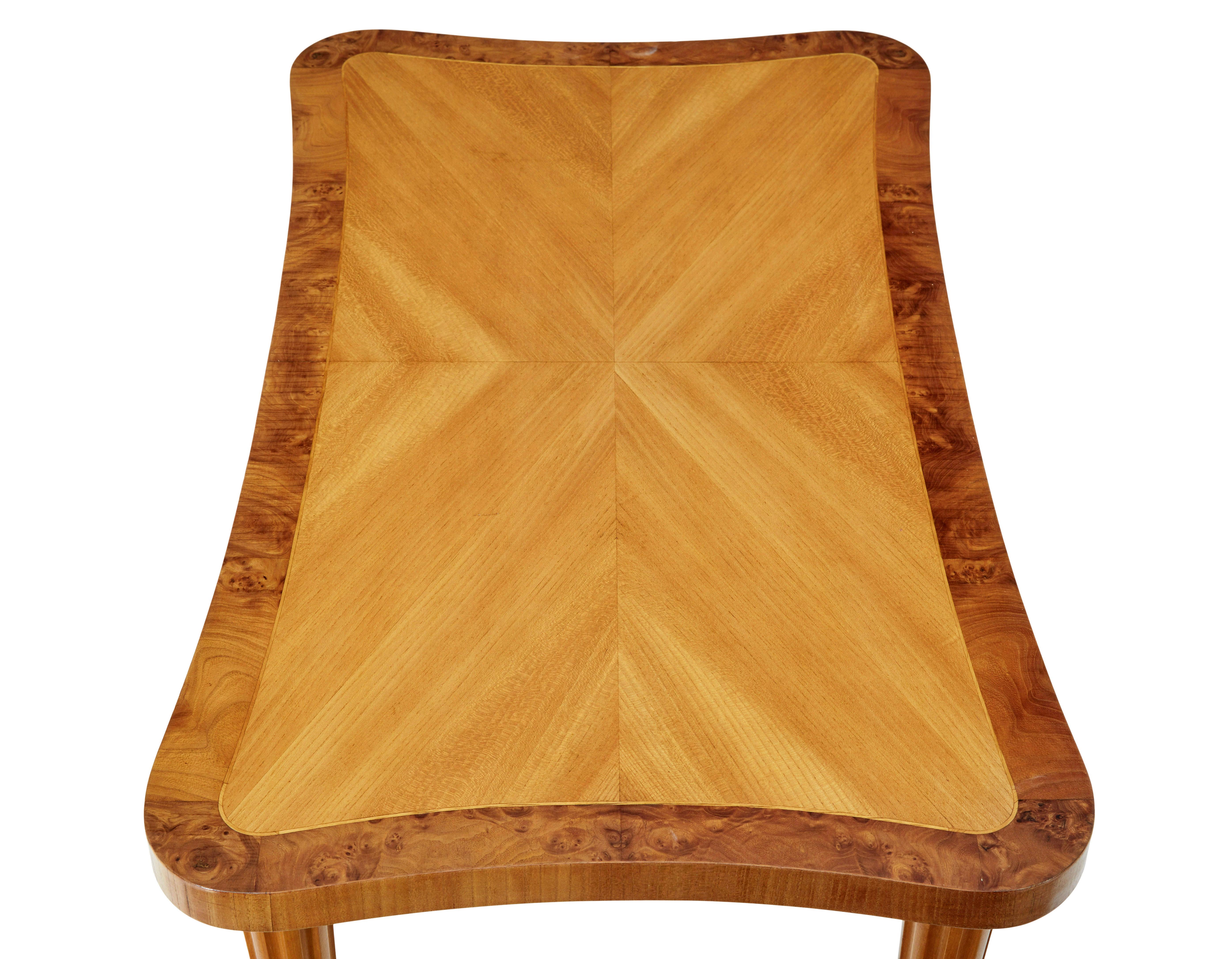 Table basse scandinave en forme de bouleau du milieu du 20e siècle, vers 1950.

Côtés concaves inhabituels.  Plateau en bouleau plaqué sur quartier avec bordure extérieure en ronce de noyer.

Elle repose sur 4 pieds cannelés et effilés.

Marques de