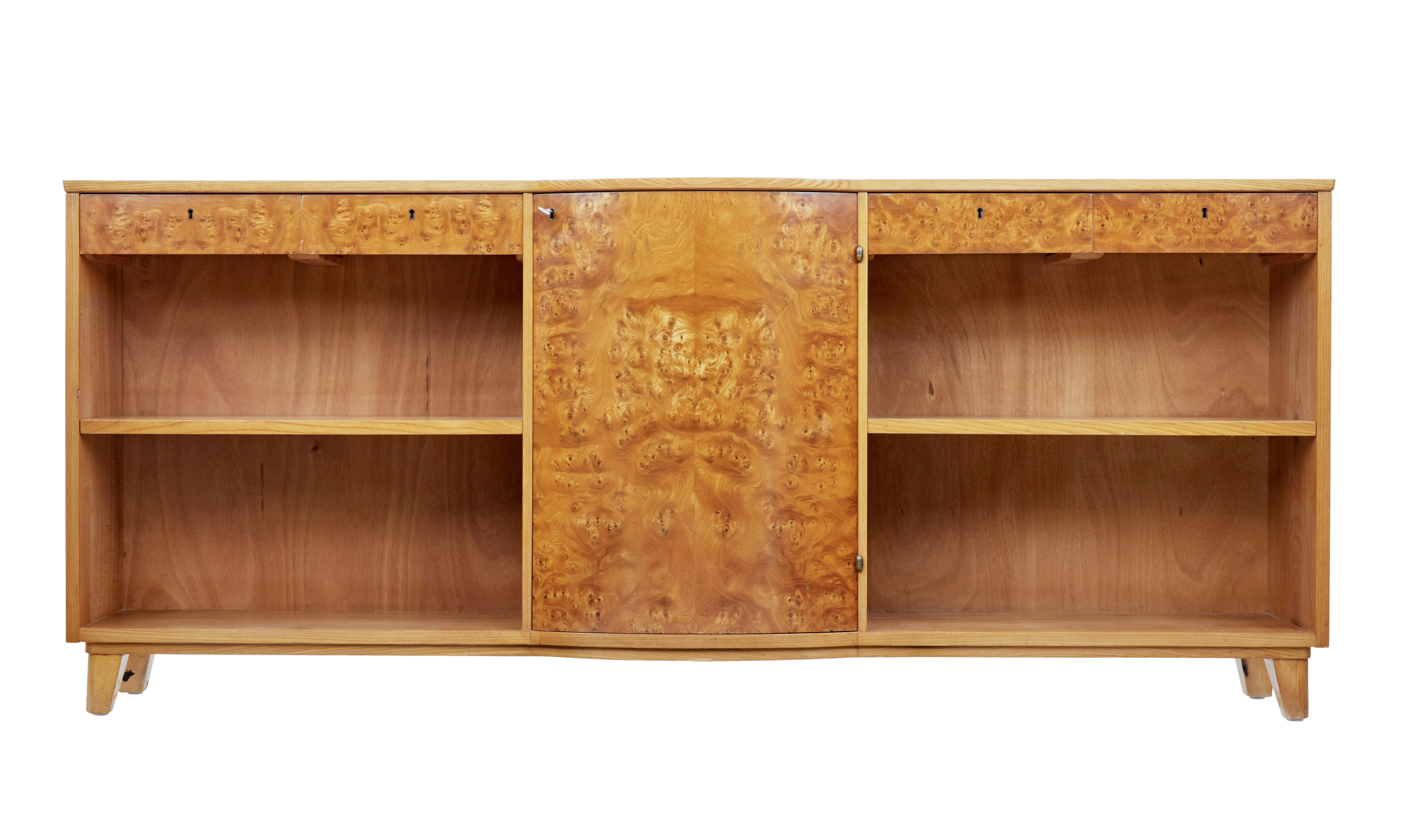 Large and impressive Scandinavian low bookcase, circa 1950.

Bowfront burr veneer central door which contains 2 shelves. Flanked either side with 2 drawers below the top surface and a single shelf for book storage.

Working locks and key.