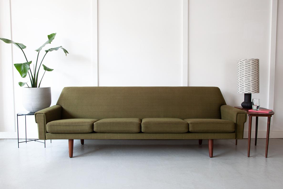 A striking four seater Danish sofa with solid teak legs in beautiful vintage condition. Classically midcentury in style with angular, clean lines and a relaxed, comfortable stance. The original green tweed upholstery is in good condition and the