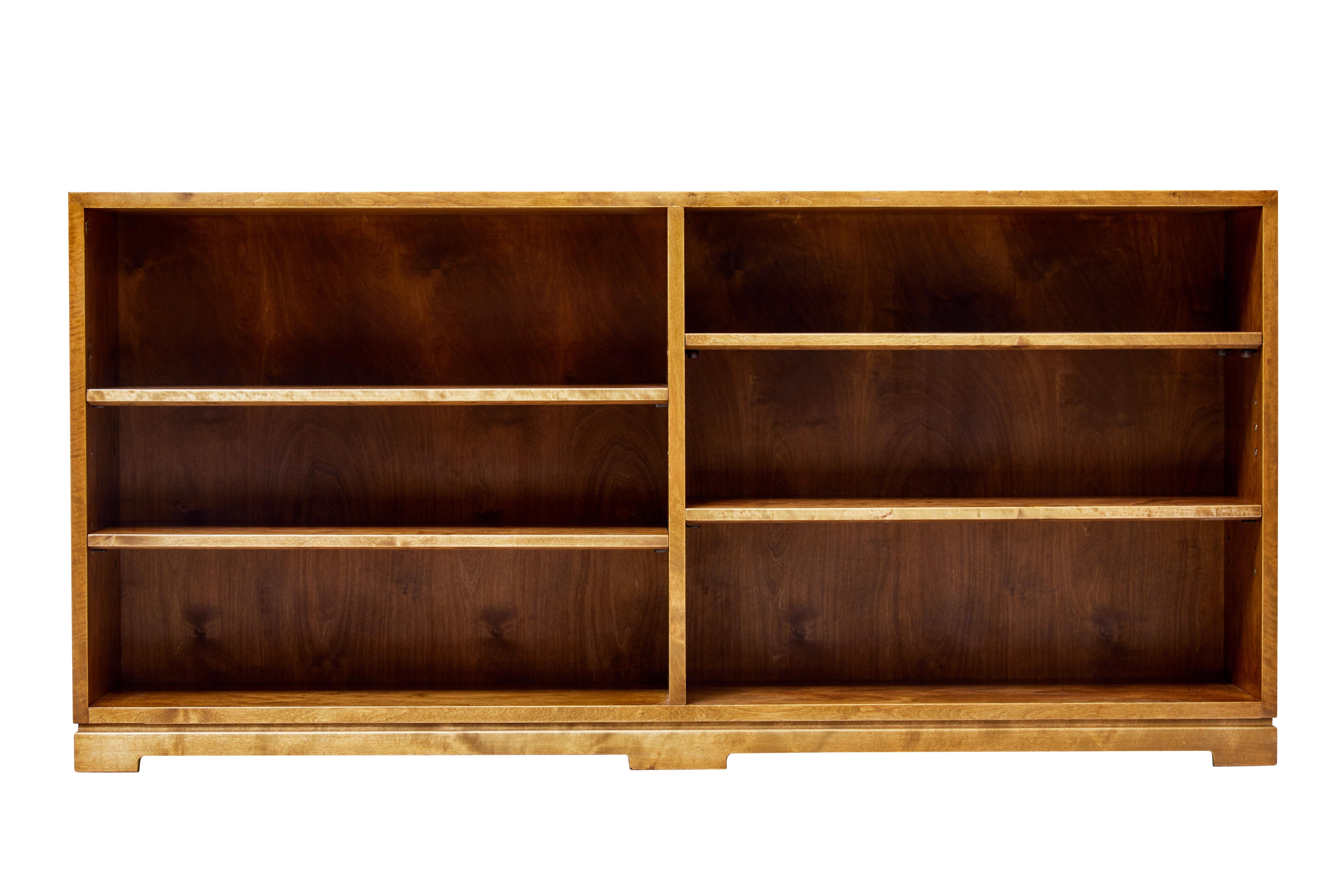 Simple and elegant low open bookcase, circa 1940.

Two shelves either side of a central partition. Each shelf is fully adjustable to allow accommodation of different book sizes.

Recently restored back to its former golden rich color.
