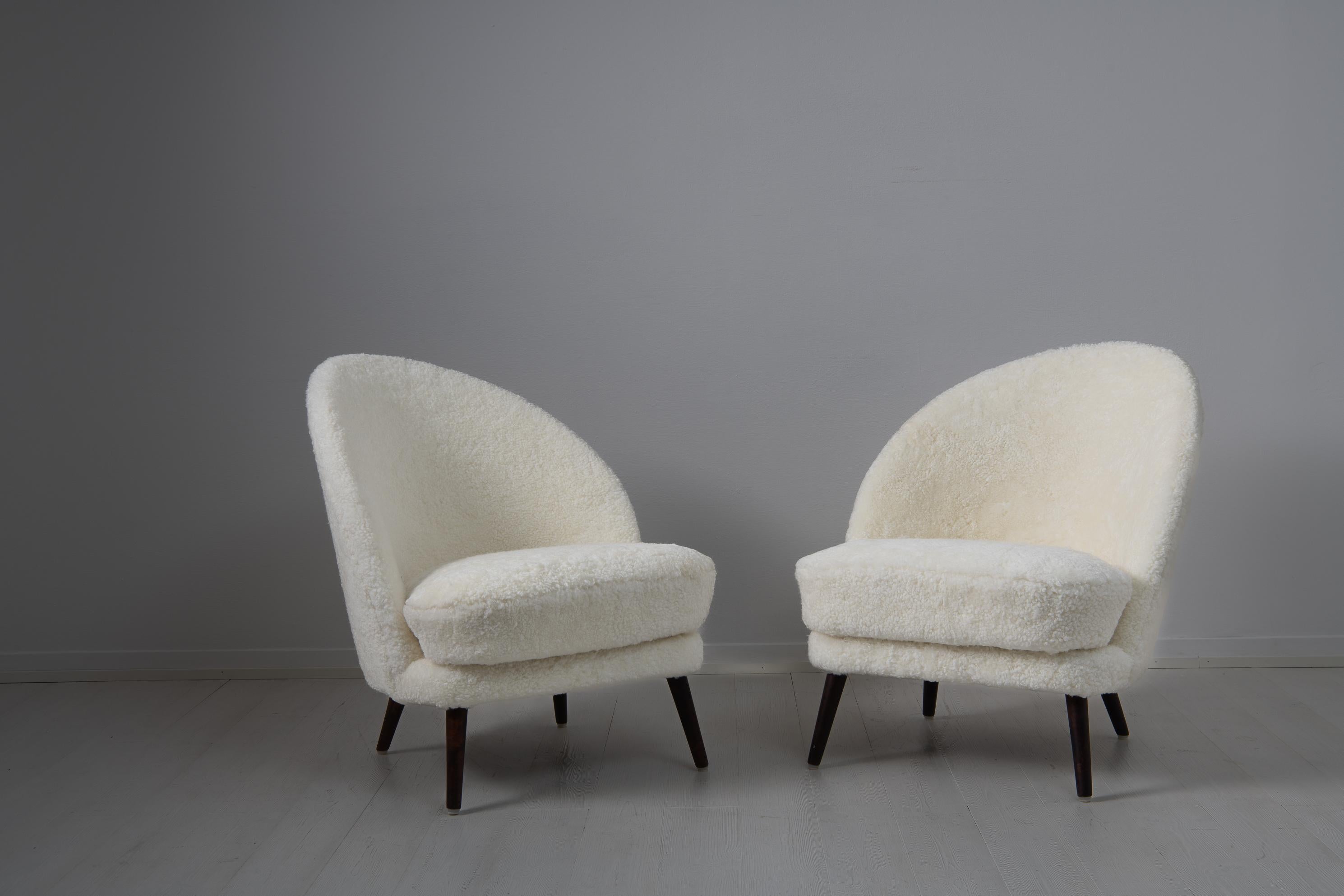 Scandinavian modern sheepskin chairs attributed to Arne Norell, Sweden from the mid 20th century. The chairs have an asymmetrical back and legs in stained birch. The design is clean and classic with the asymmetry creating extra interest and a twist.