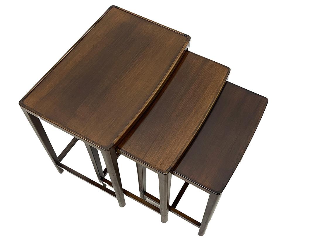 Mid 20th Century Scandinavian Nesting table set

A set of Scandinavian nesting tables in dark nut wooden color. 
Rectangular tables with a slightly curved shape at the front. The large table has a glass top and the smallest shows some scratches.