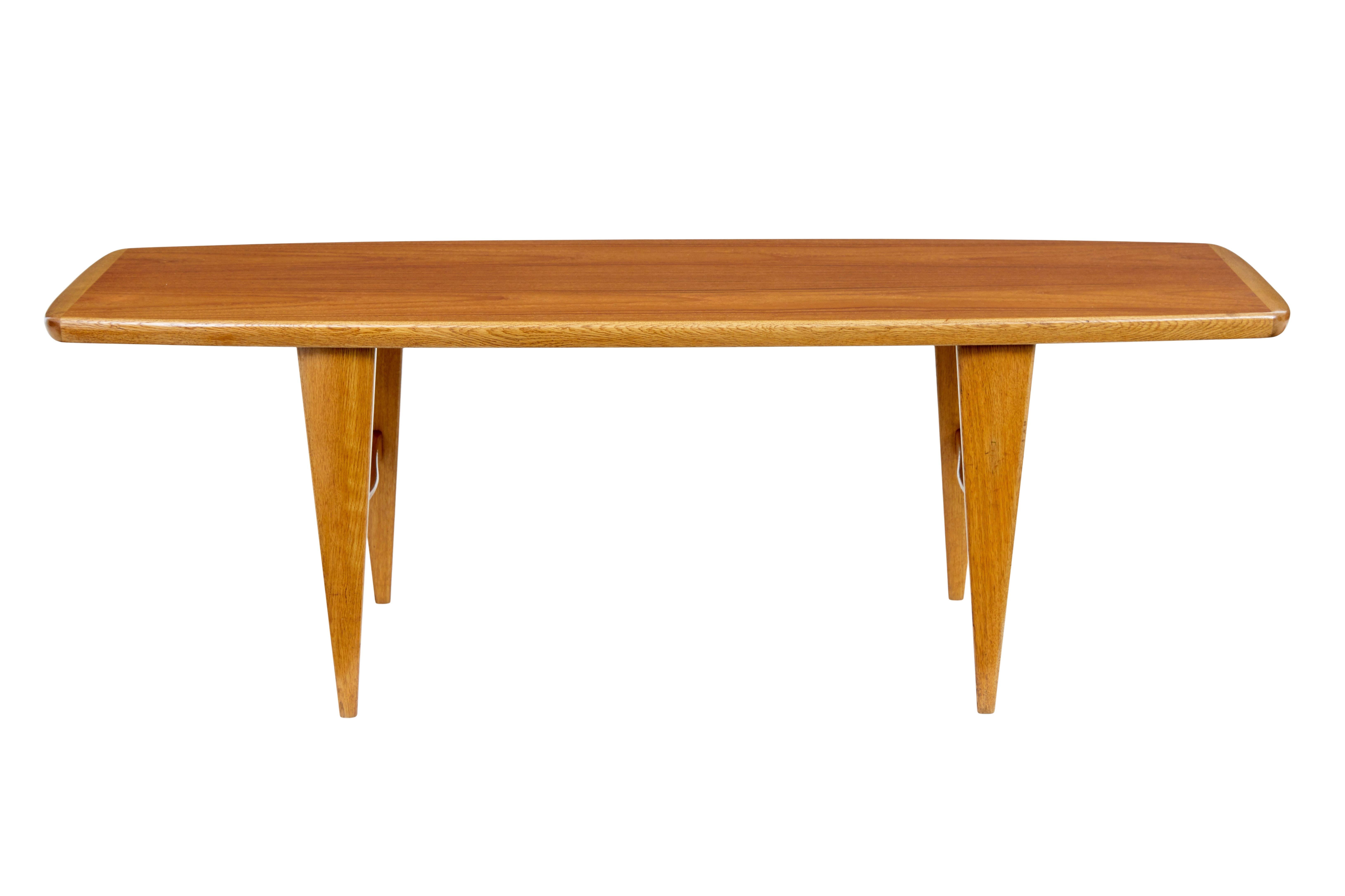 Tavolino in teak scandinavo della metà del XX secolo, circa 1960.

Elegante tavolino da caffè sagomato in teak e Oak.  Piano in teak con bordo in Oak.  Si regge su gambe affusolate in Oak unite da un telaio a H. H. sagomato.

1 area di lieve usura