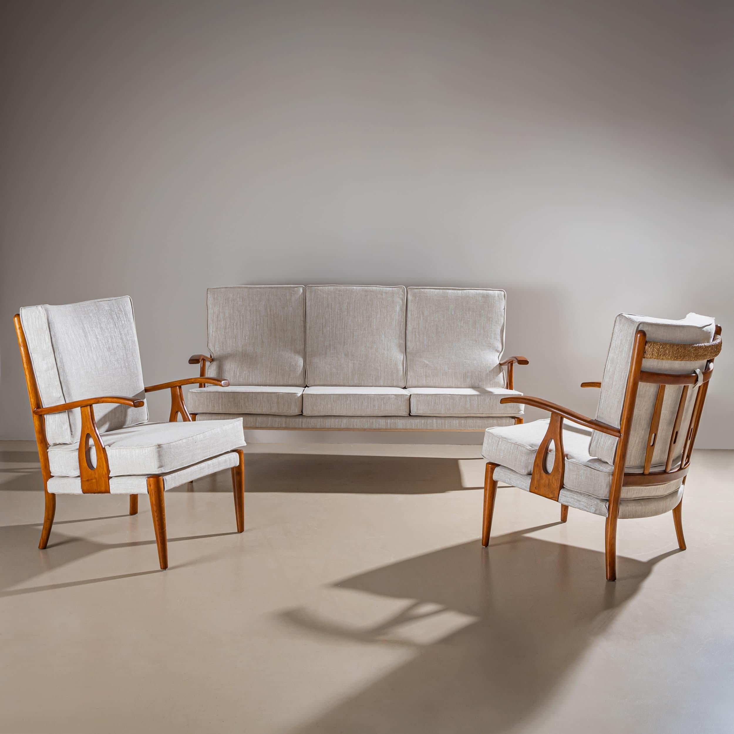 Set composto da un divano a tre posti e due poltrone abbinate, caratterizzate da braccioli elegantemente curvati e telai in legno finemente lavorati. La tappezzeria è stata appena rifatta in un morbido tessuto grigio e le superfici in legno sono