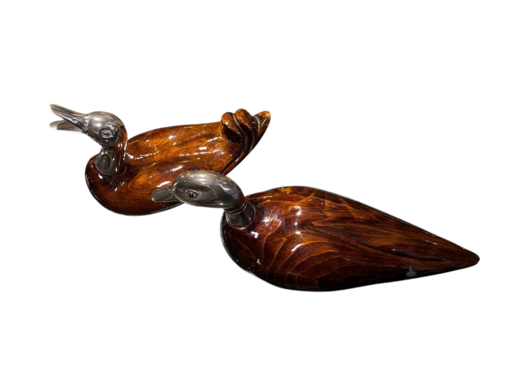 This a Pair of De Stijl Firenze Sculptures of Ducks. It depicts a pair of two ducks bodies made of glazed wood and their heads of silver. They are in a resting posture, but one of them is also ‘laughing’. Both of them are hallmarked with the Stijl