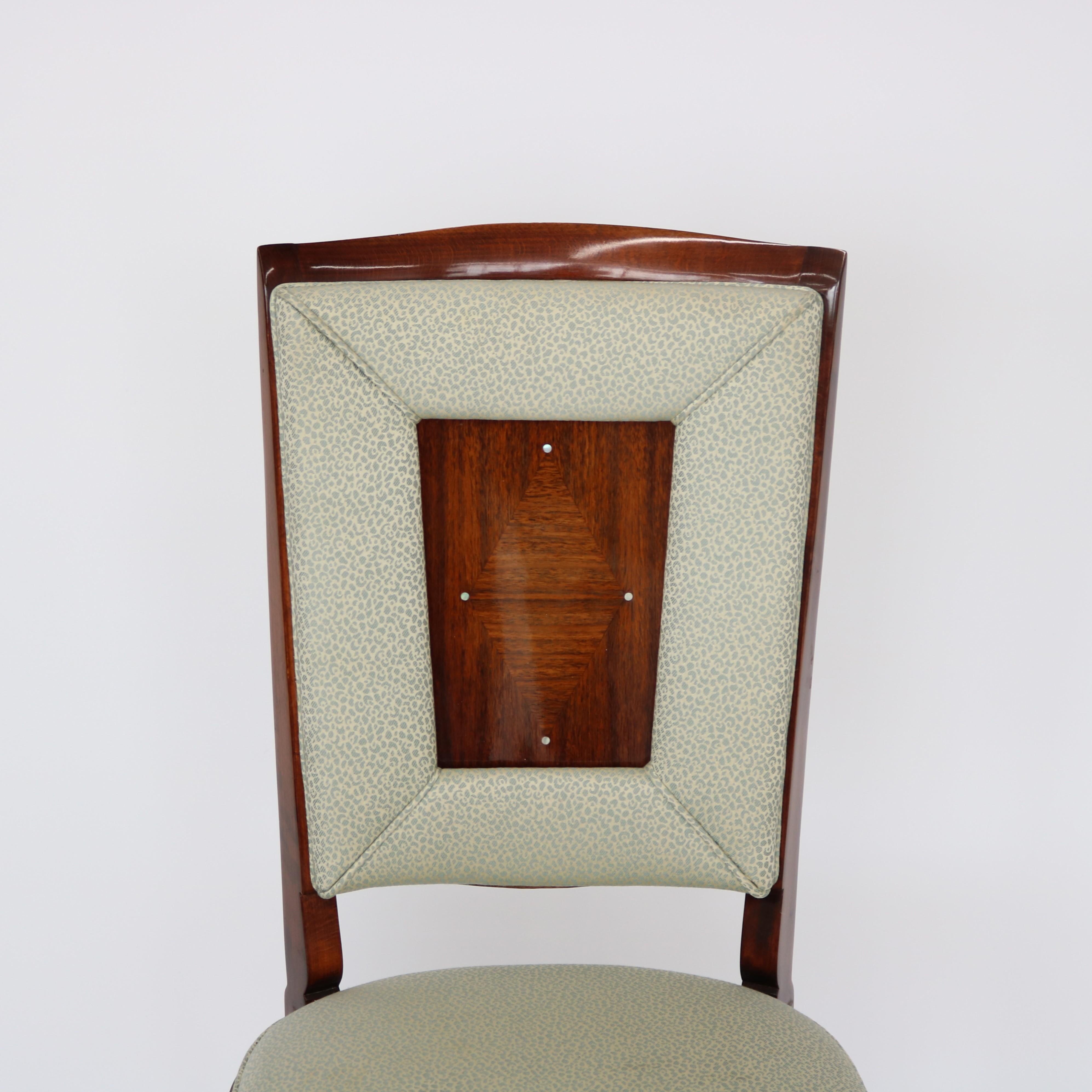 Set of Eight Dining Chairs in the style of Jules Leleu.  Hardwood frames with upholstered inset back supports.  The panel backs feature parquetry ribbon beautiful hardwood veneer in a diamond pattern with mother of pearl inlay at the corners framed