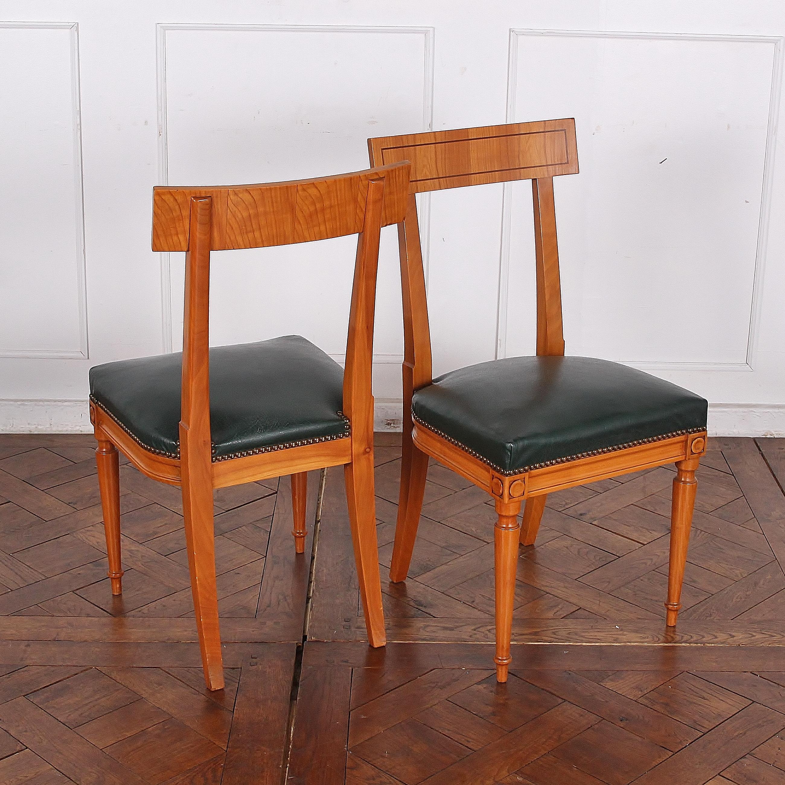 Set of eight vintage French cherrywood Directoire style dining chairs upholstered in green leather, the backs with walnut inlaid stringing and with turned tapering front legs.