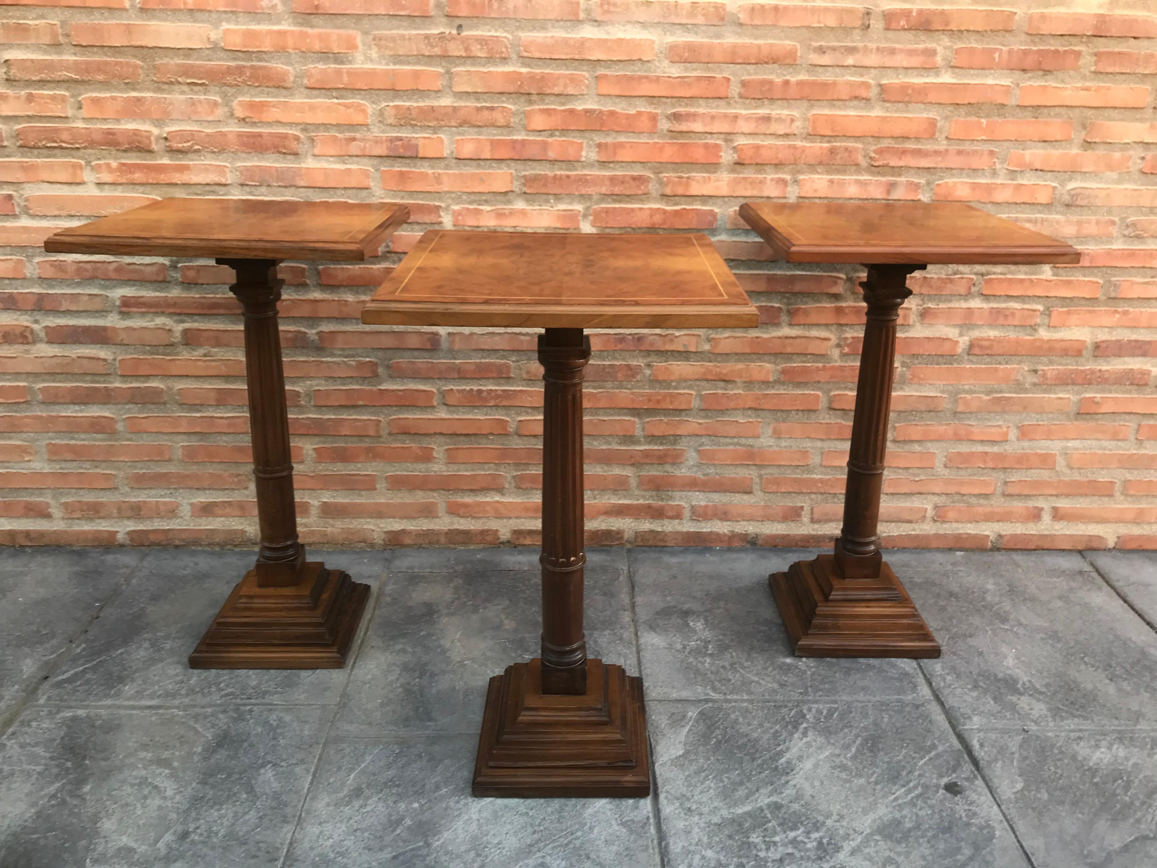 Mid-20th century set of three walnut wood square top pedestal tables.