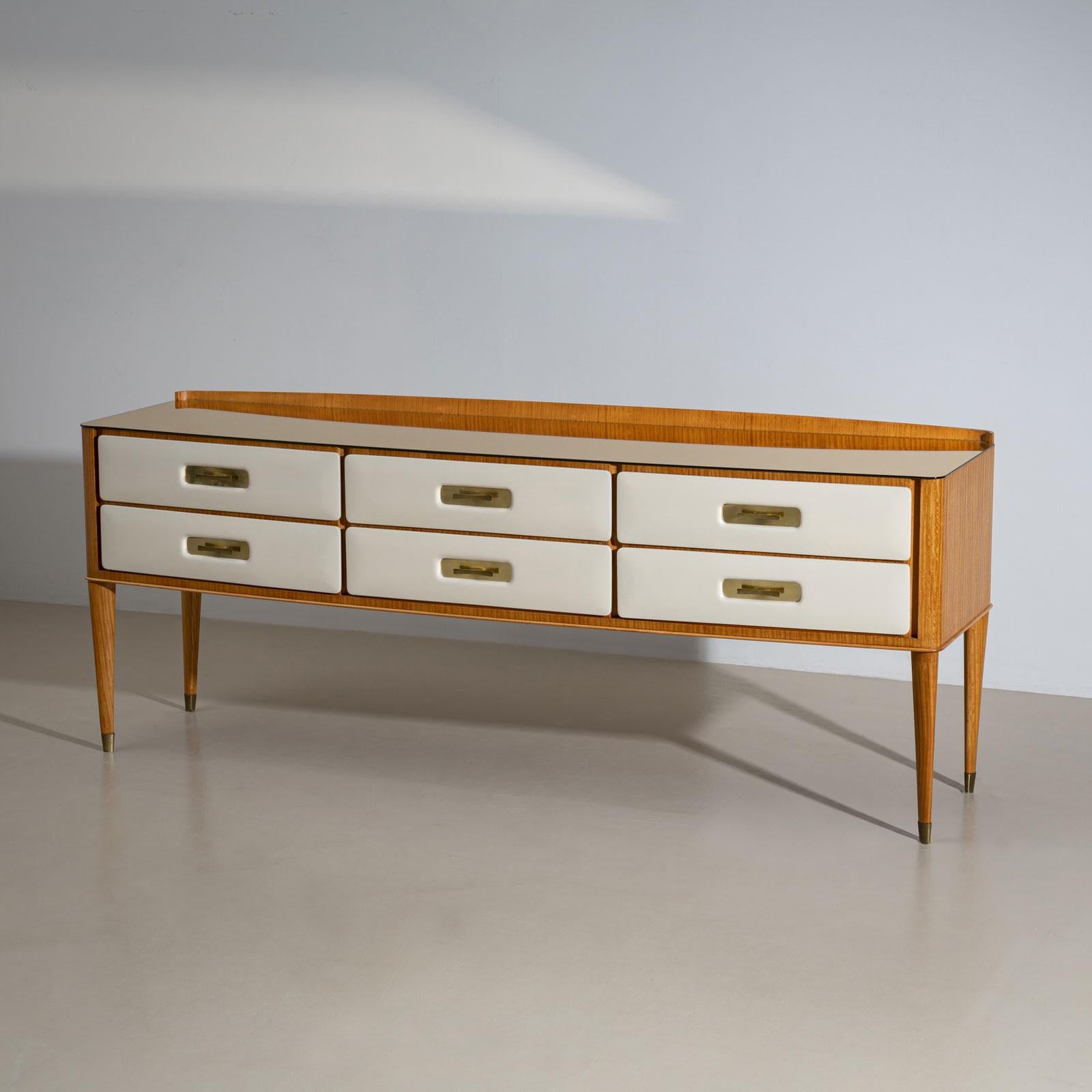 

An elegant Italian sideboard from the mid-20th century, crafted from light satinwood. The long front features six drawers, each covered in cream-white parchment, creating a stylish contrast with the wood. Fine brass handles highlight the